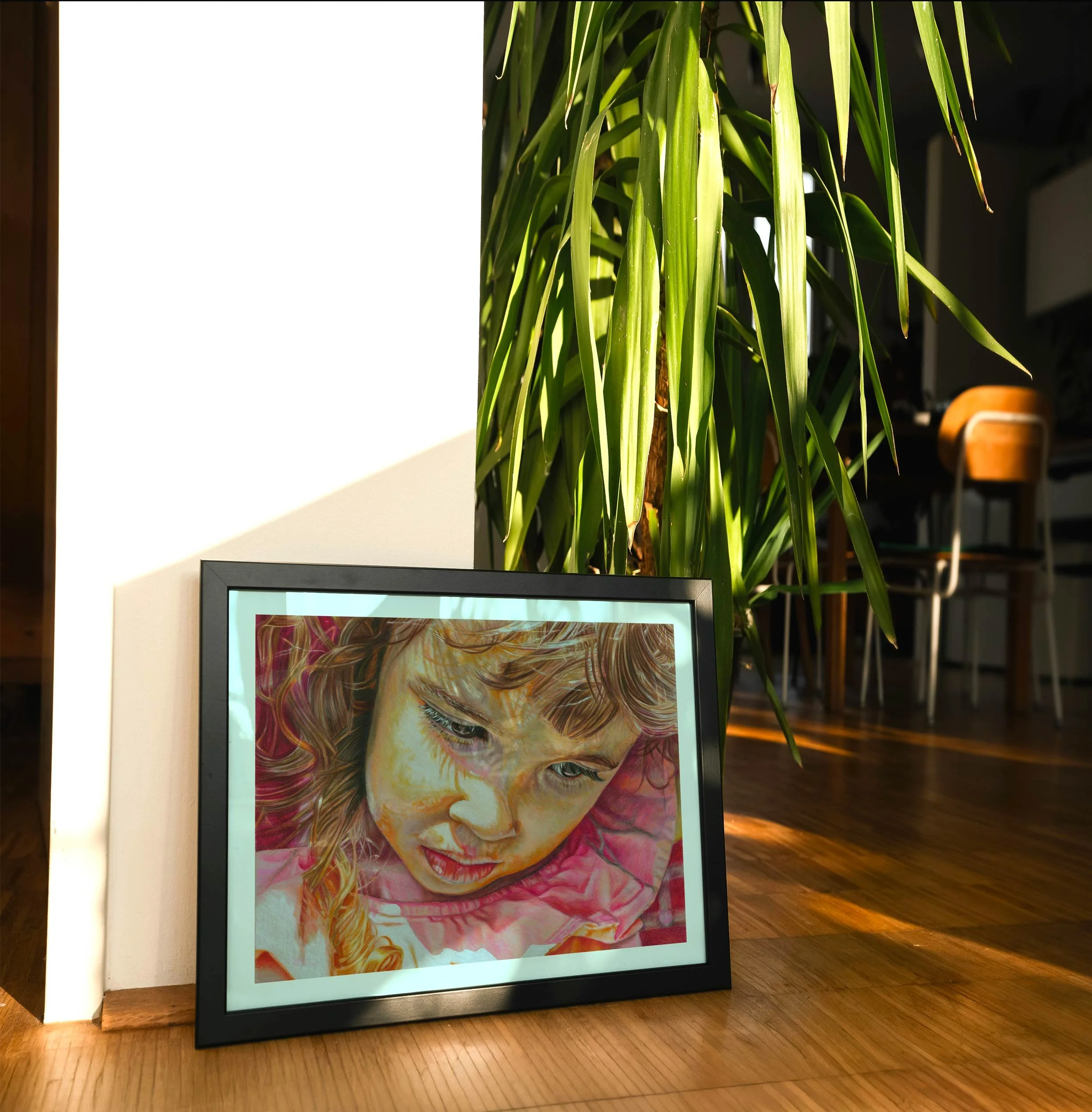 Bored colored pencil portrait print leaning on a wood floor in warm sunlight