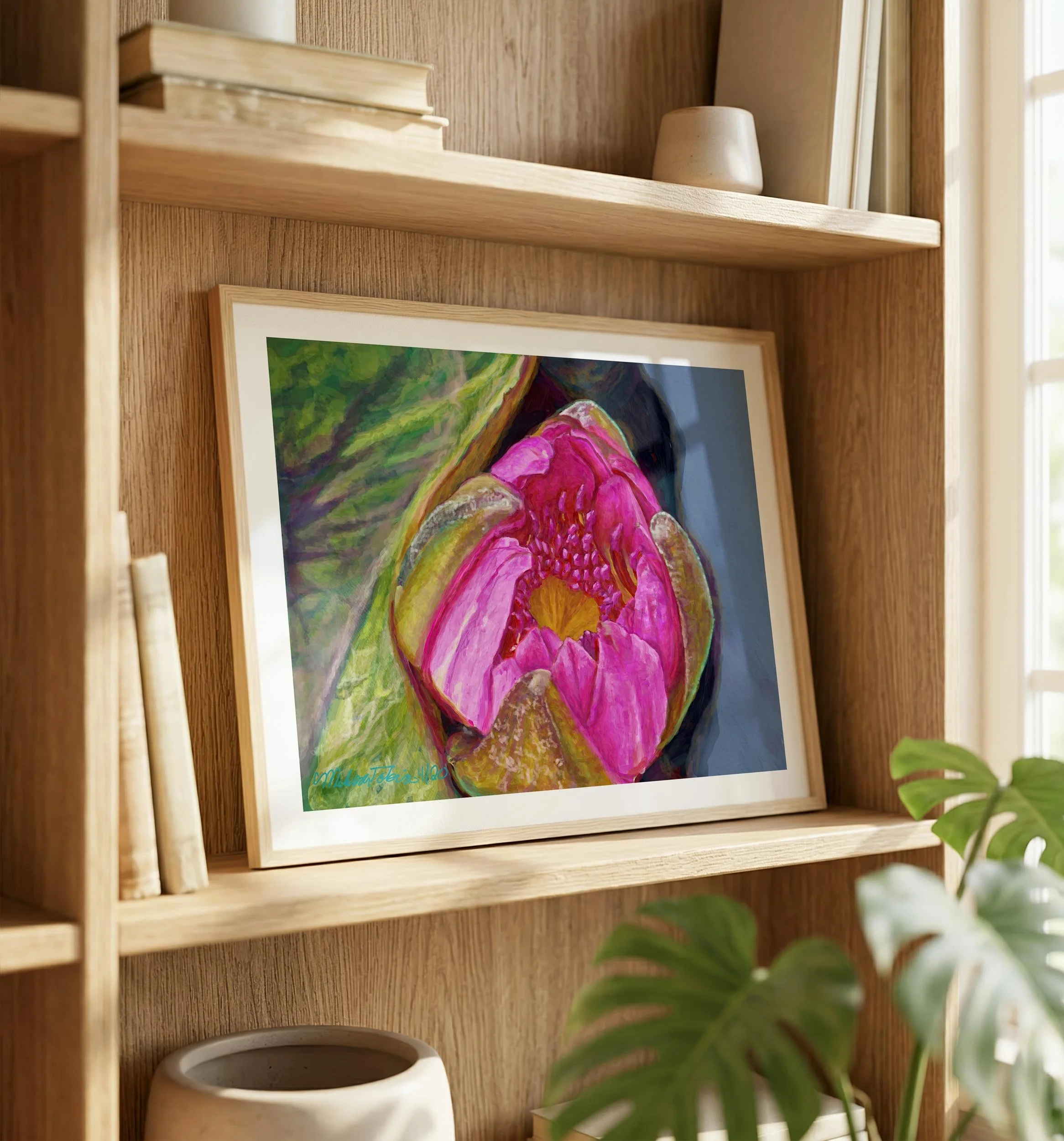 Framed water lily print resting on a wood shelving unit beside ceramics and a monstera leaf