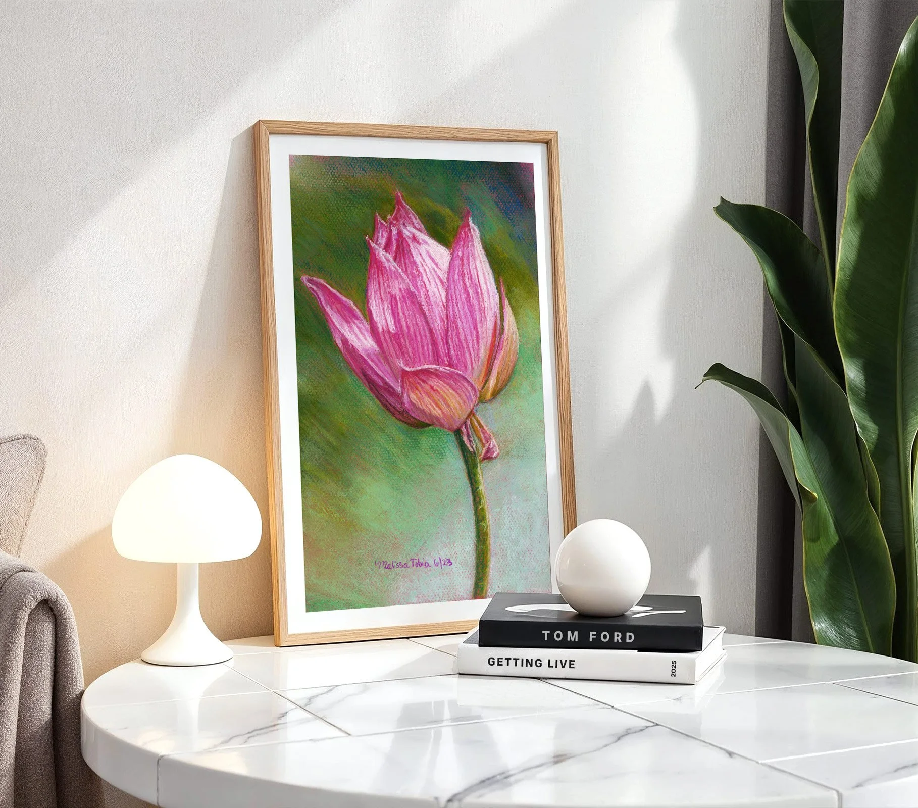 Lotus flower art print on a white side table with a lamp and book