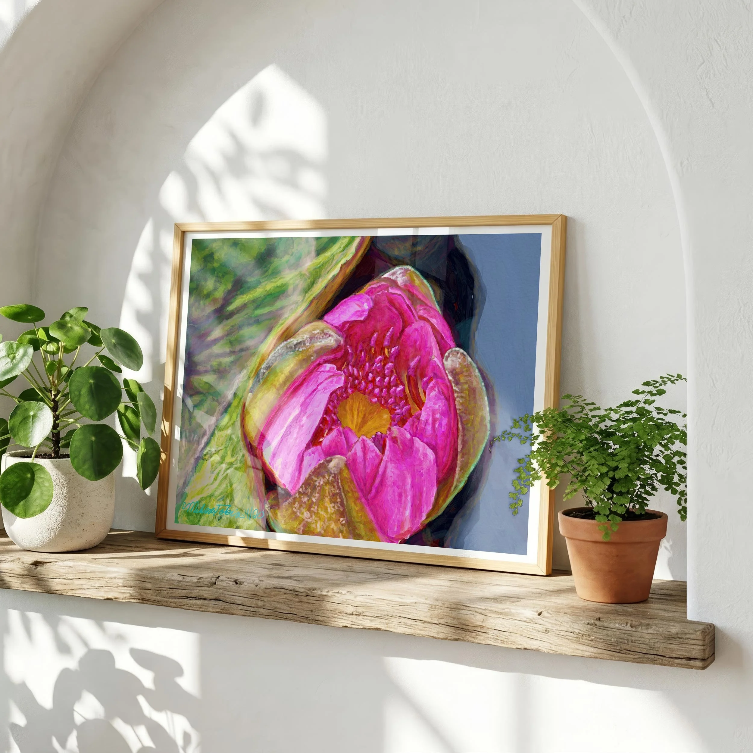 A framed art print featuring a close-up of a pink water lily. The artwork is displayed on a wooden shelf, with a potted plant on either side.