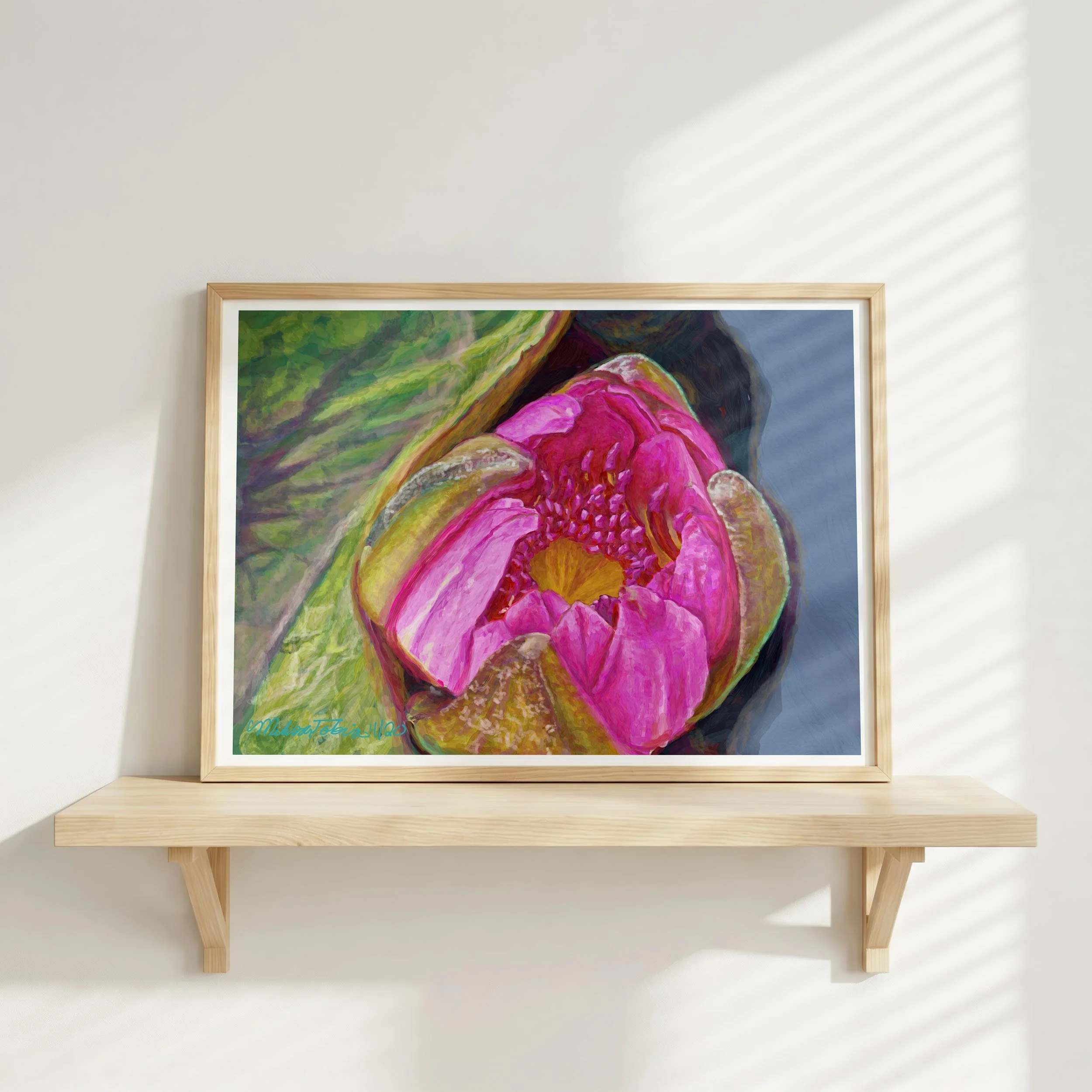 Pink water lily wall art in a light wood frame on a floating shelf against a white wall