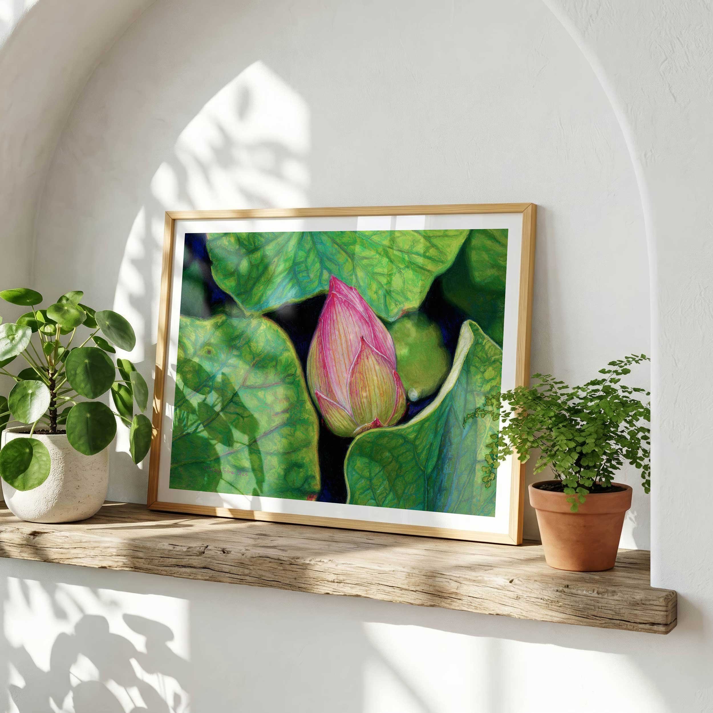 Framed pink lotus pastel print displayed on a wooden shelf with plants  against a white wall in a neutral, minimalist living room