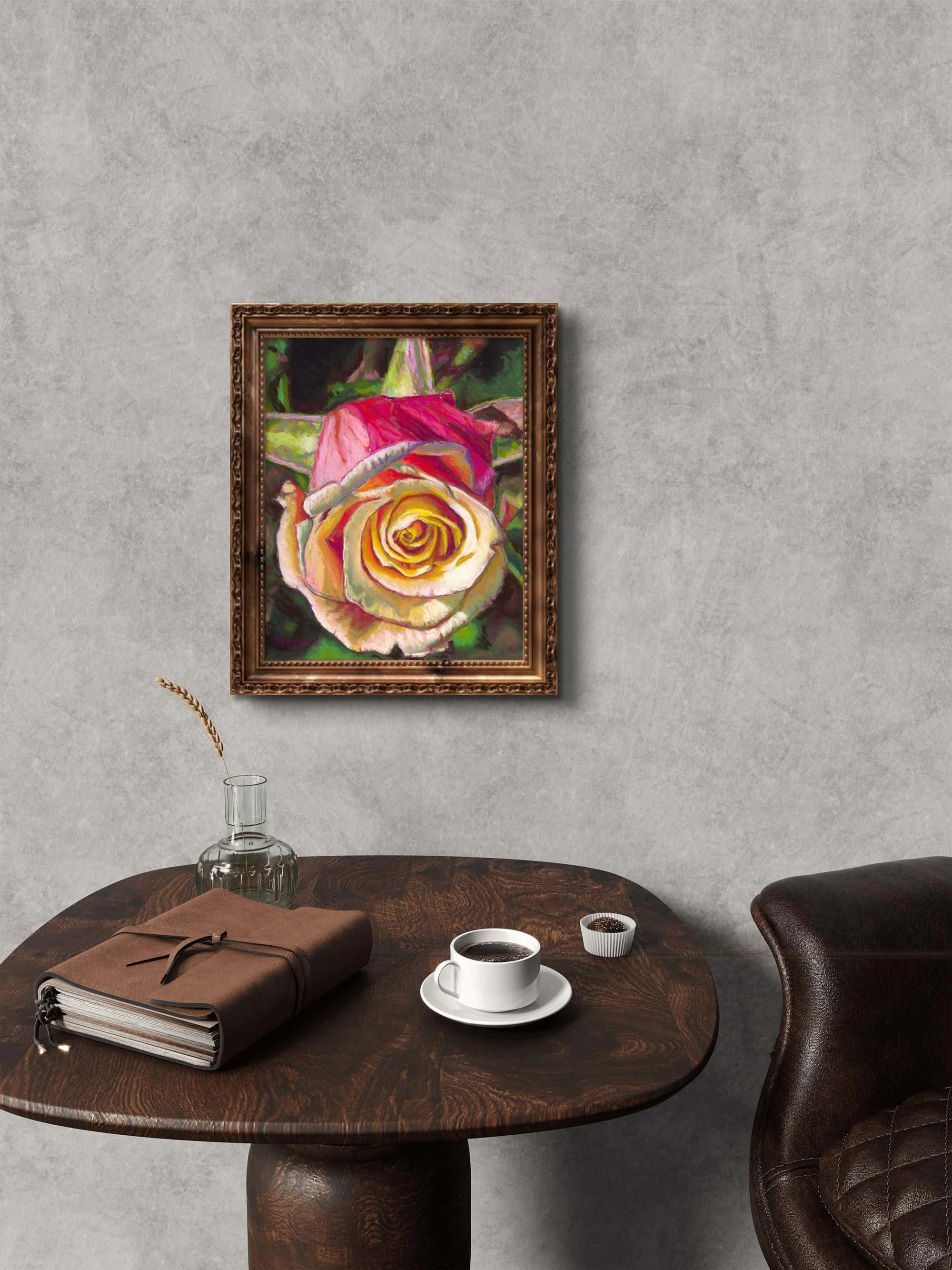 Framed rose pastel hanging above a round wood table with a coffee cup and a leather journal