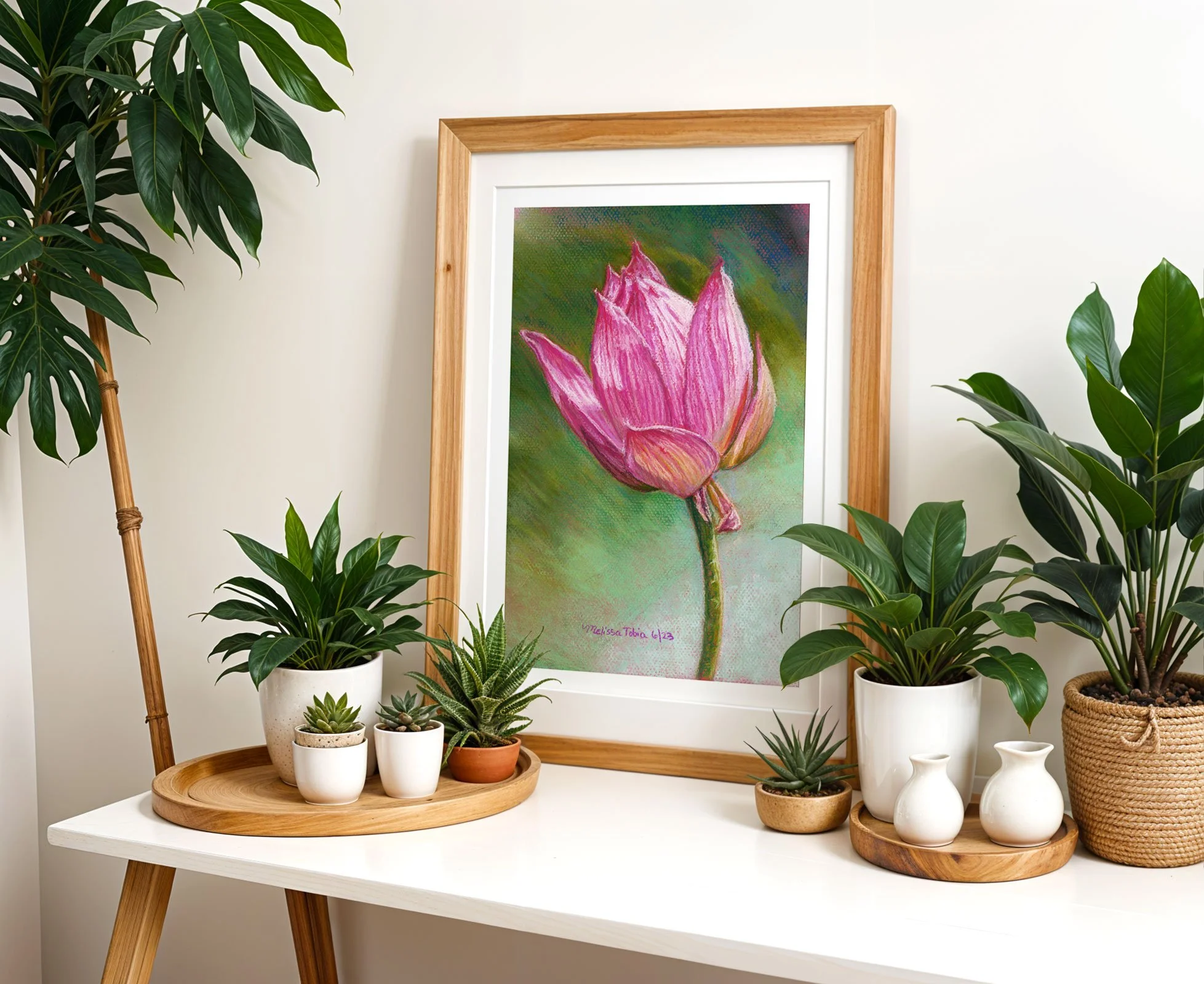 Lotus flower art print on a white desk surrounded by potted plants