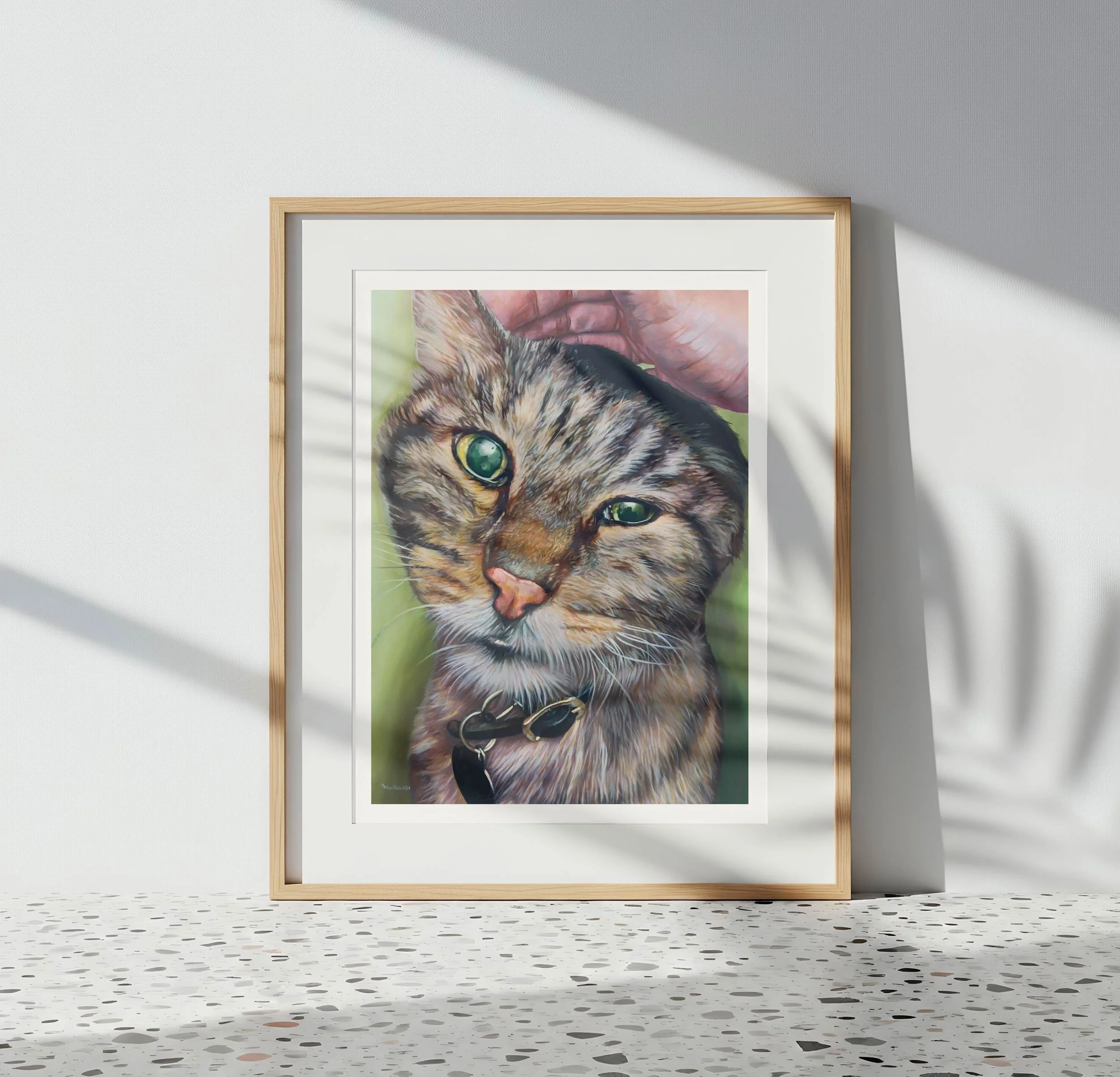 Framed tabby cat oil painting print leaning against a terrazzo tile floor