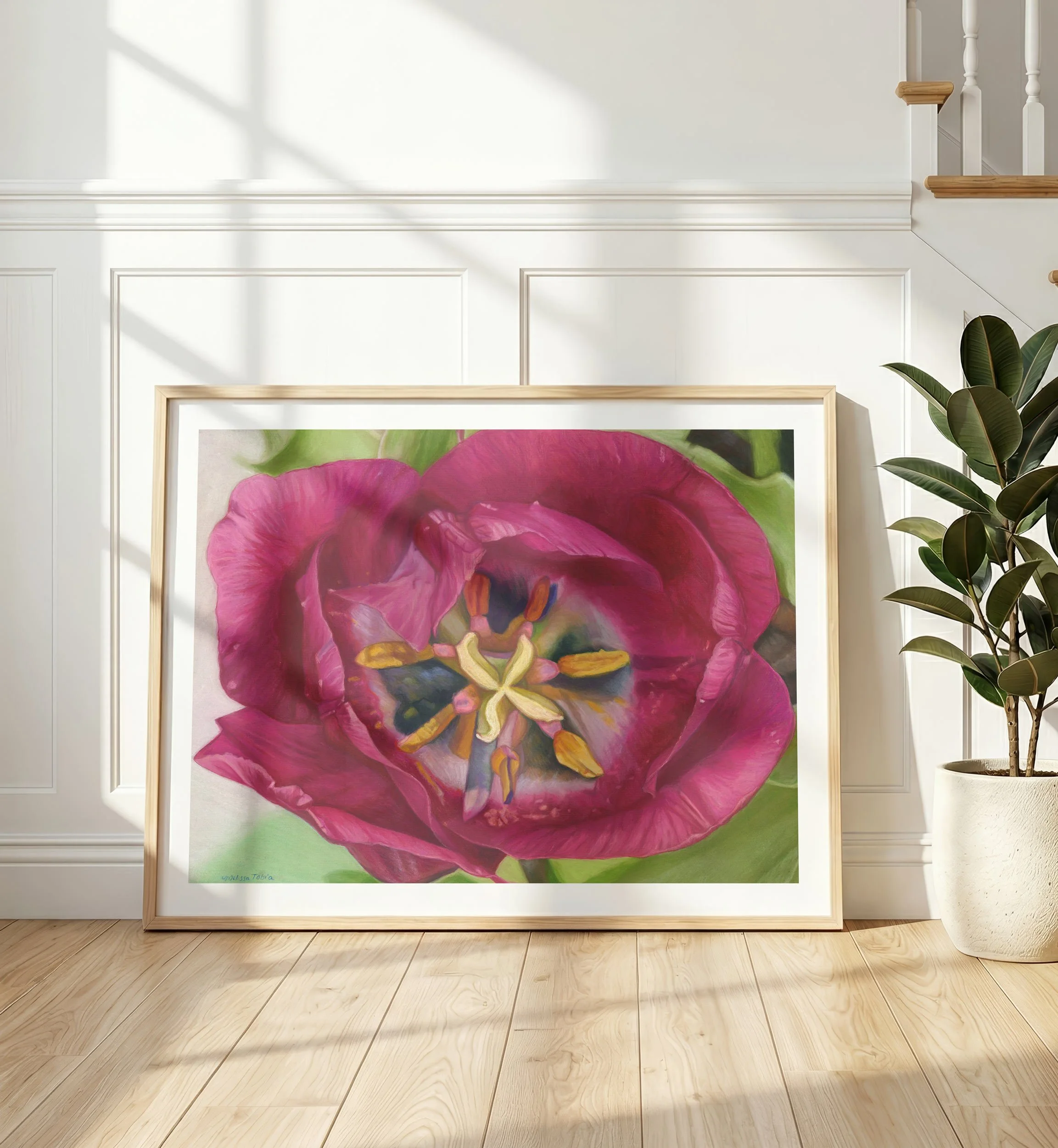 Purple tulip print in a white frame leaning against a wall in a bright white room with a plant