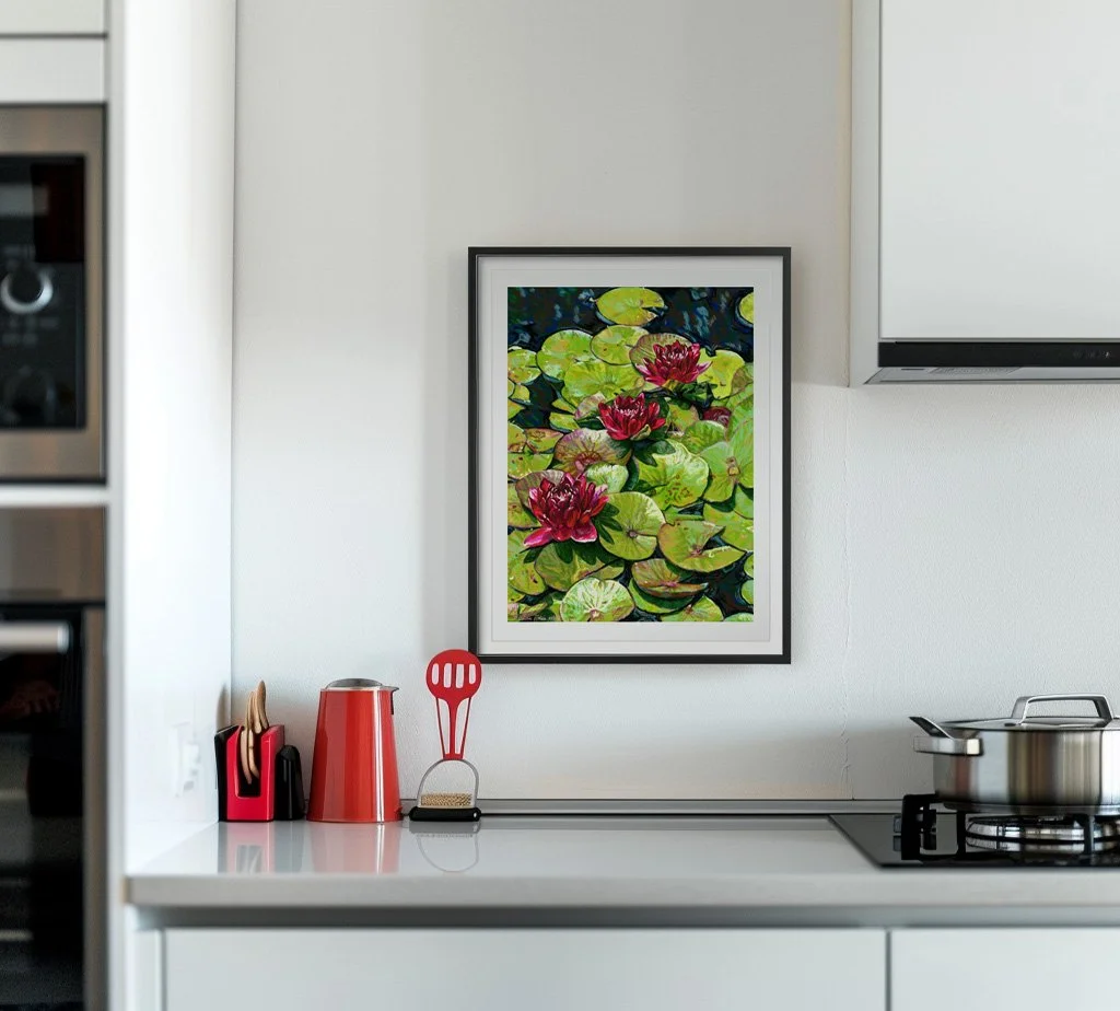 Red water lily print in a black frame hung on a white kitchen wall above a counter