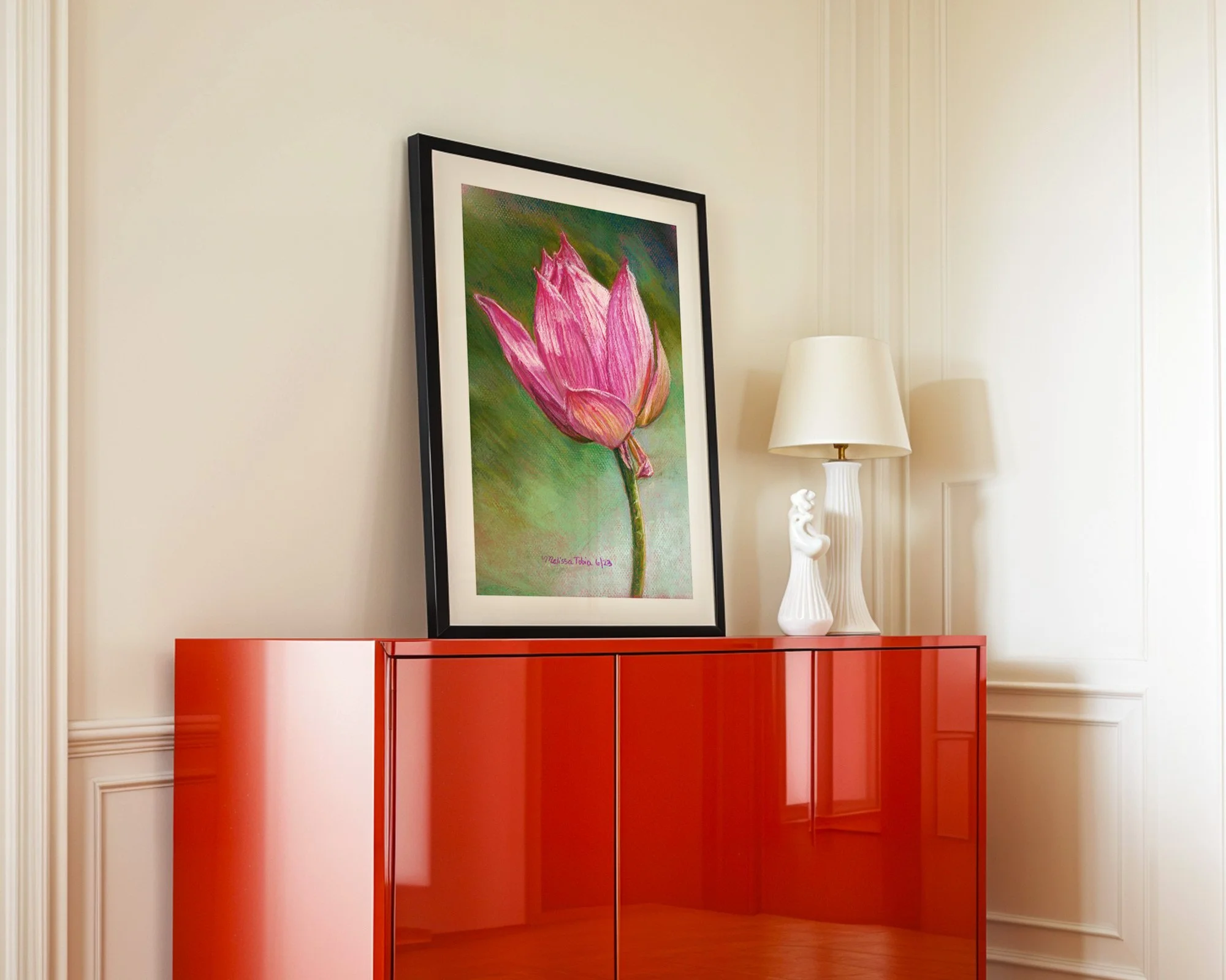 Framed pink lotus print displayed on a glossy red cabinet