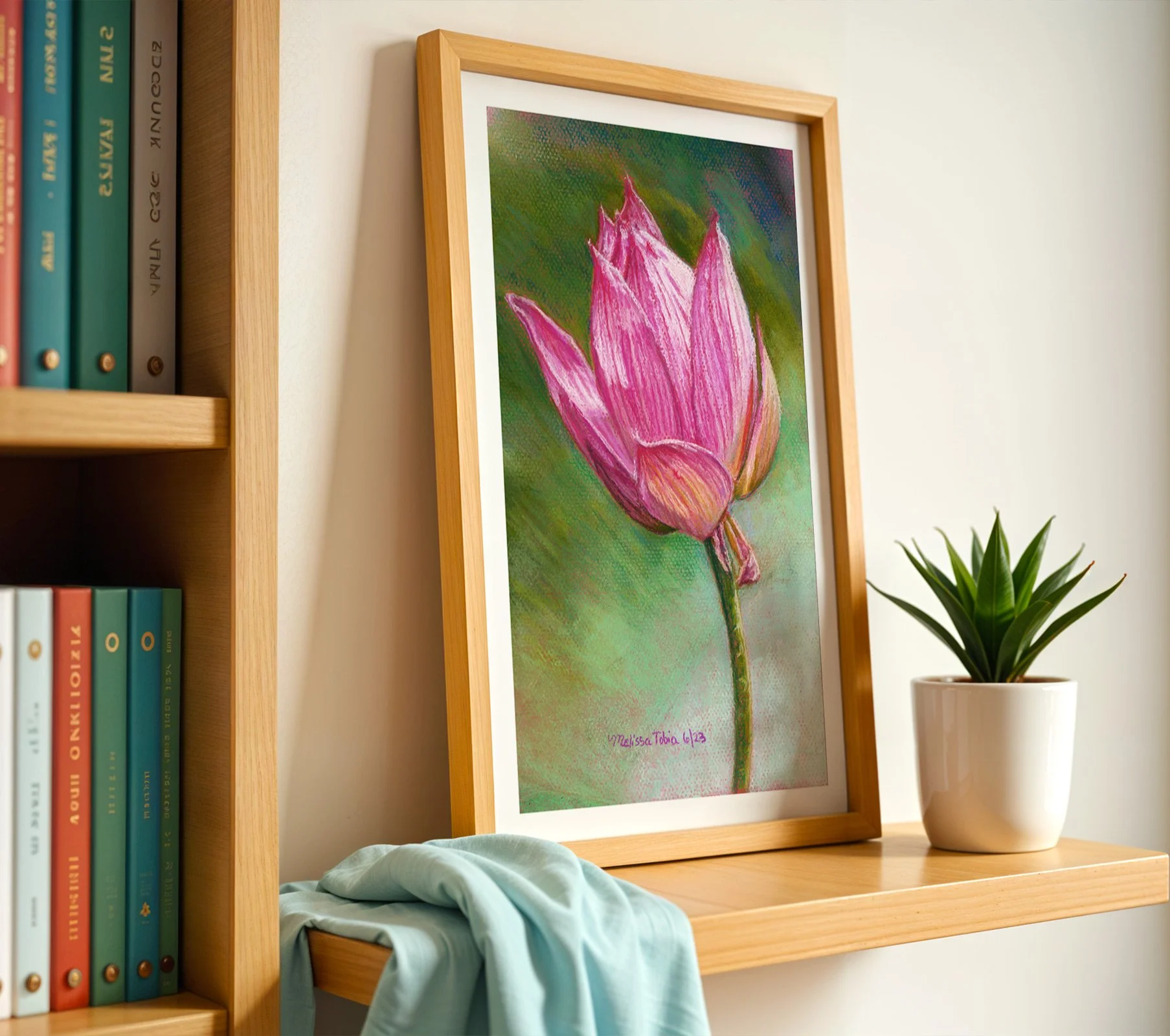 Pink lotus painting print on a bookshelf with books and a folded throw