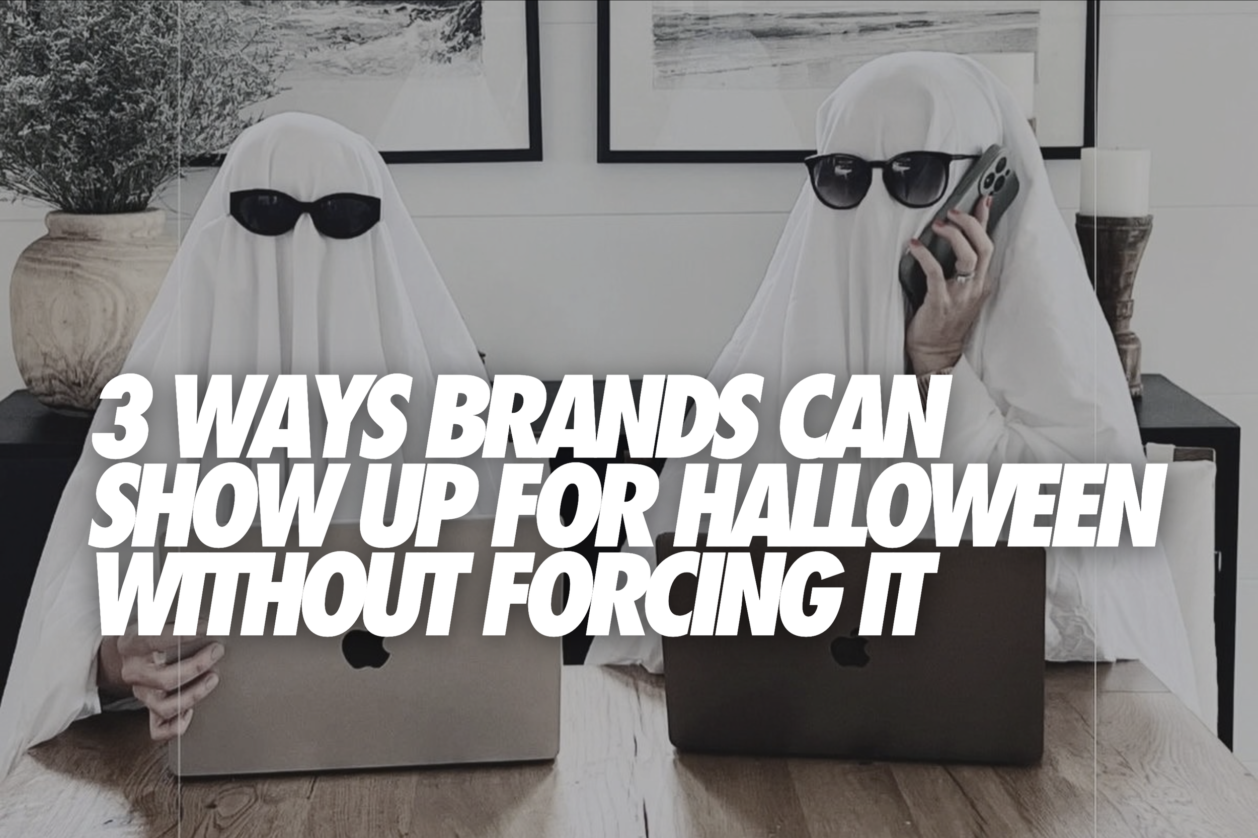 Two people dressed as ghosts in sunglasses working on laptops - Halloween marketing blog banner for TIME Marketing