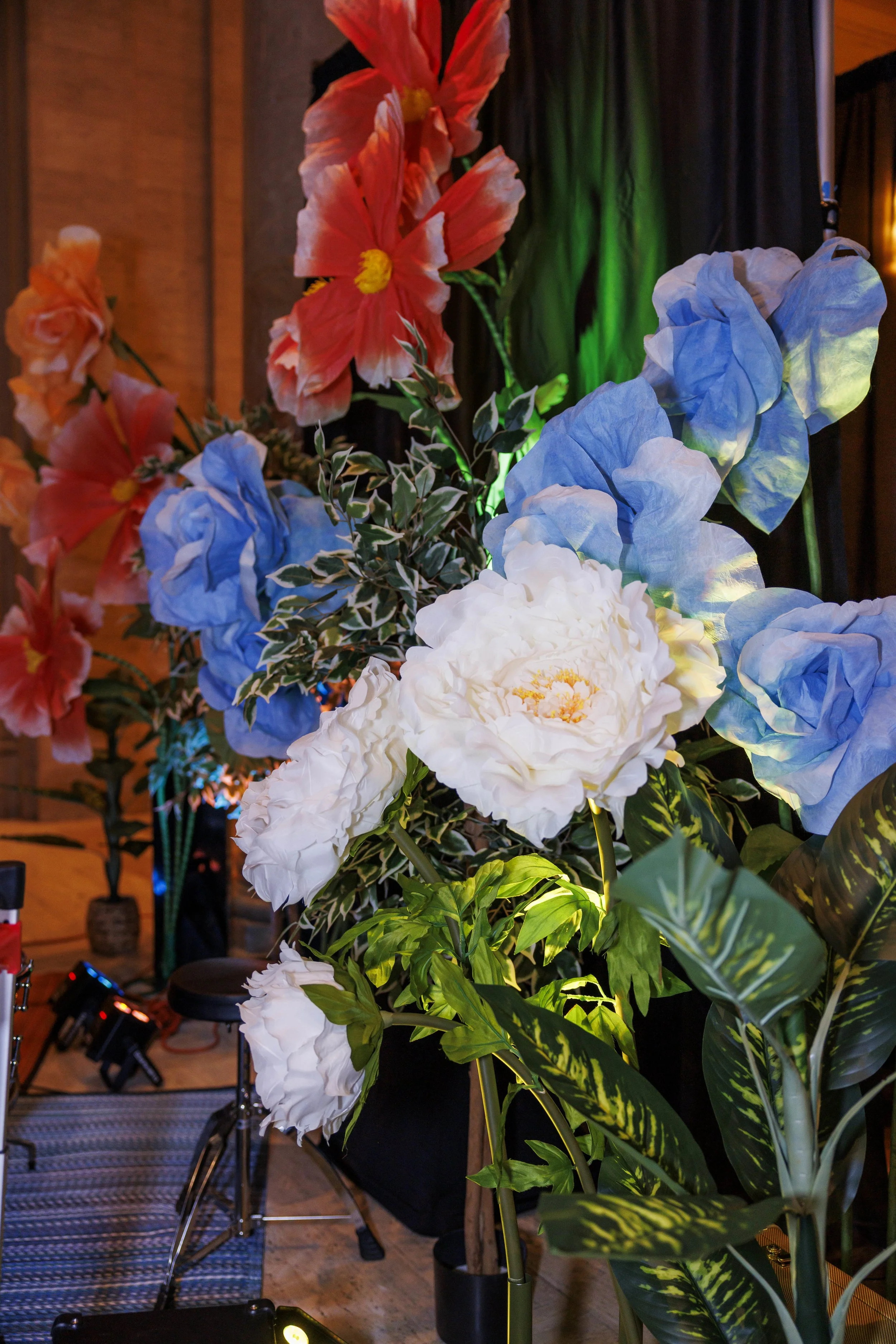 collection of giant flowers in orange blue and white as backdrop for stage performance