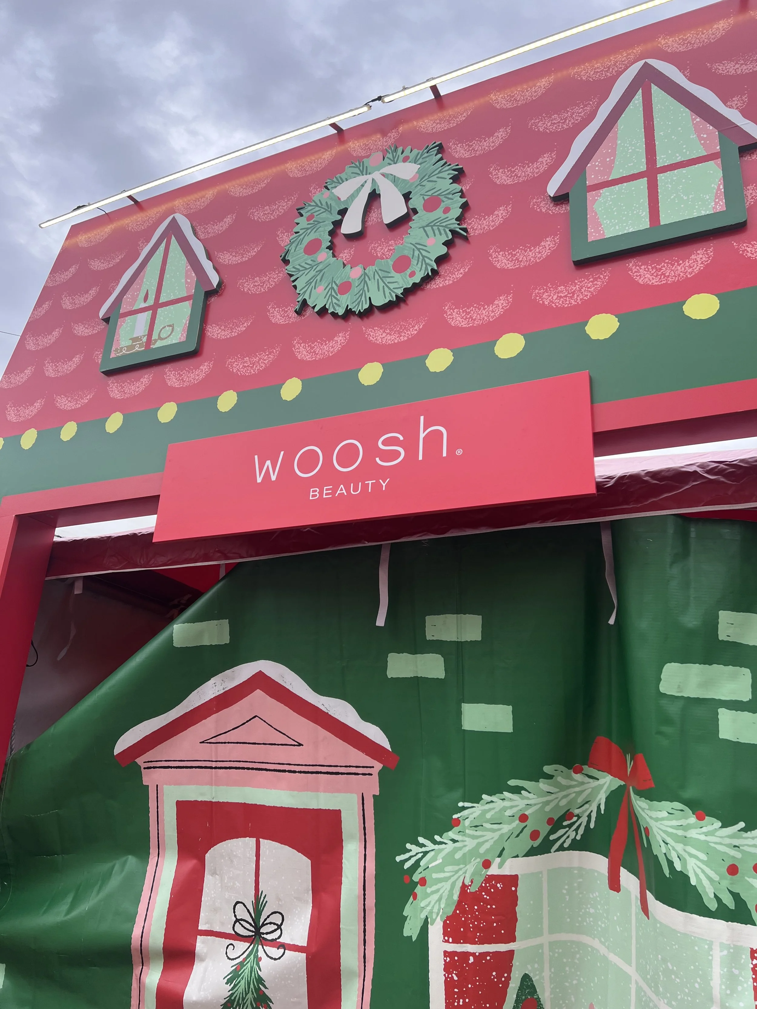 woosh beauty sign on outside of vendor booth with stylized christmas illustrations