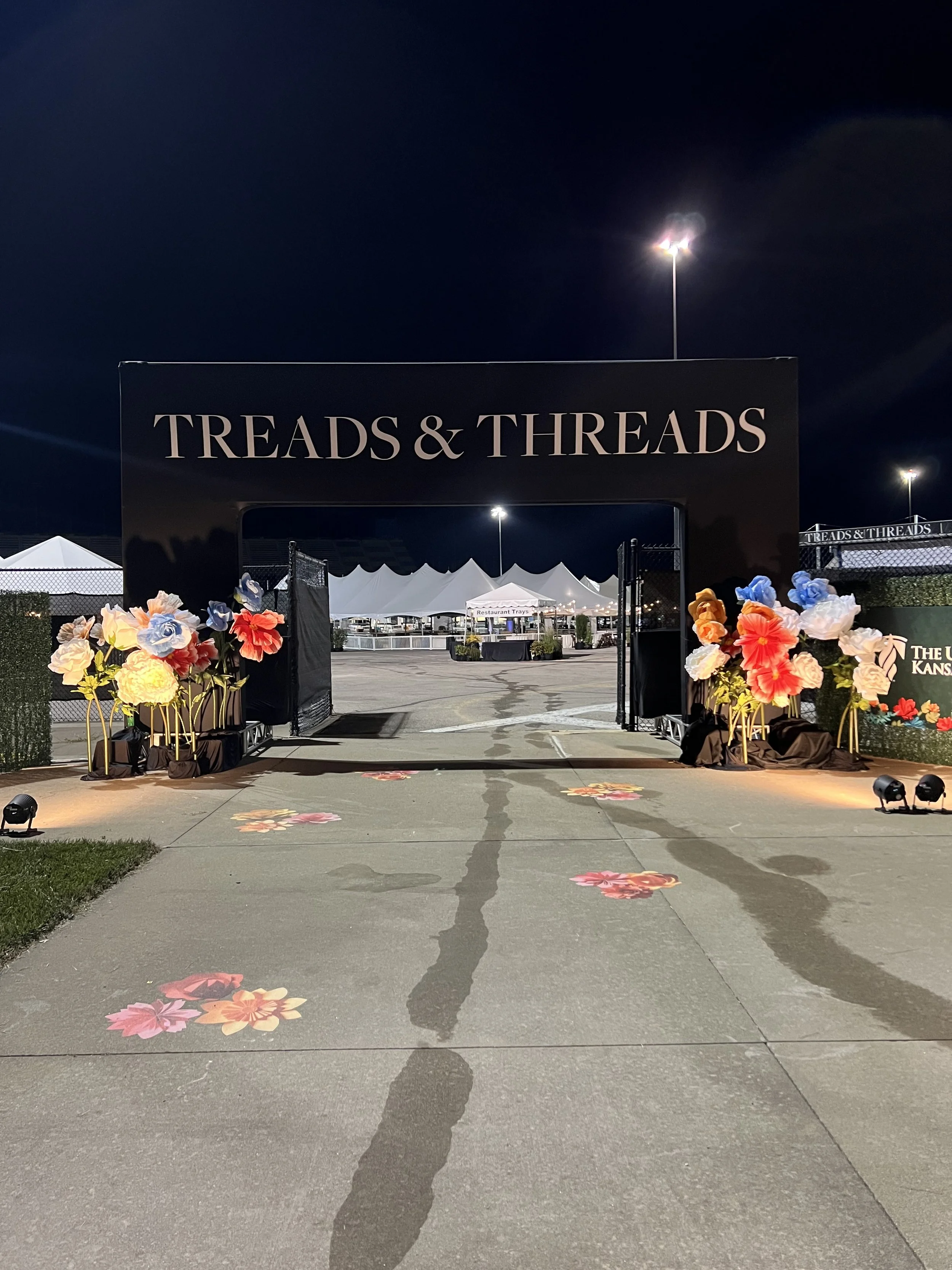 arch reaching treads and threads with giant flowers in front, during night time