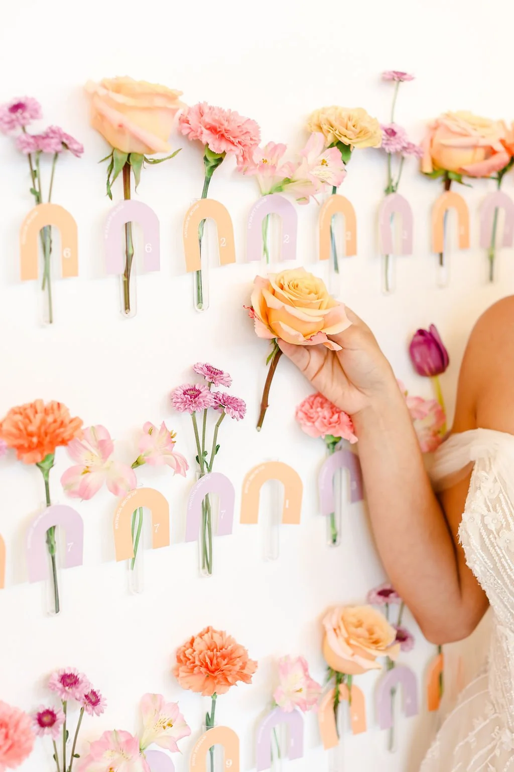 close up of colorful flower seating chart escort display with arched place cards in orange and lavender