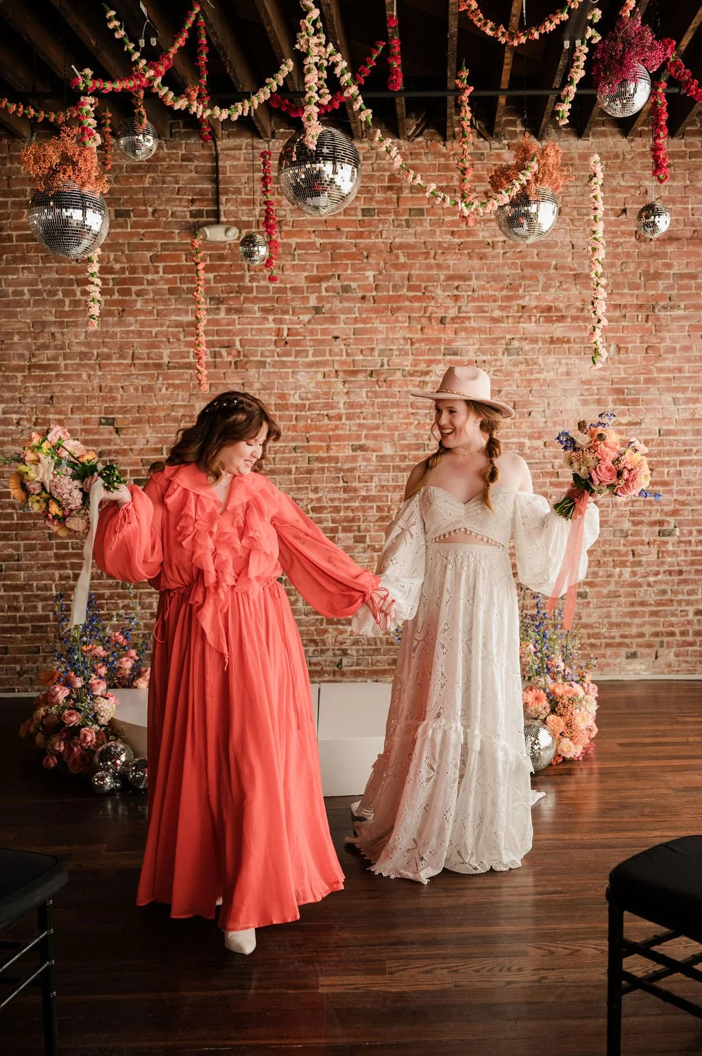 two women in dresses holding flowers in front of wedding ceremony