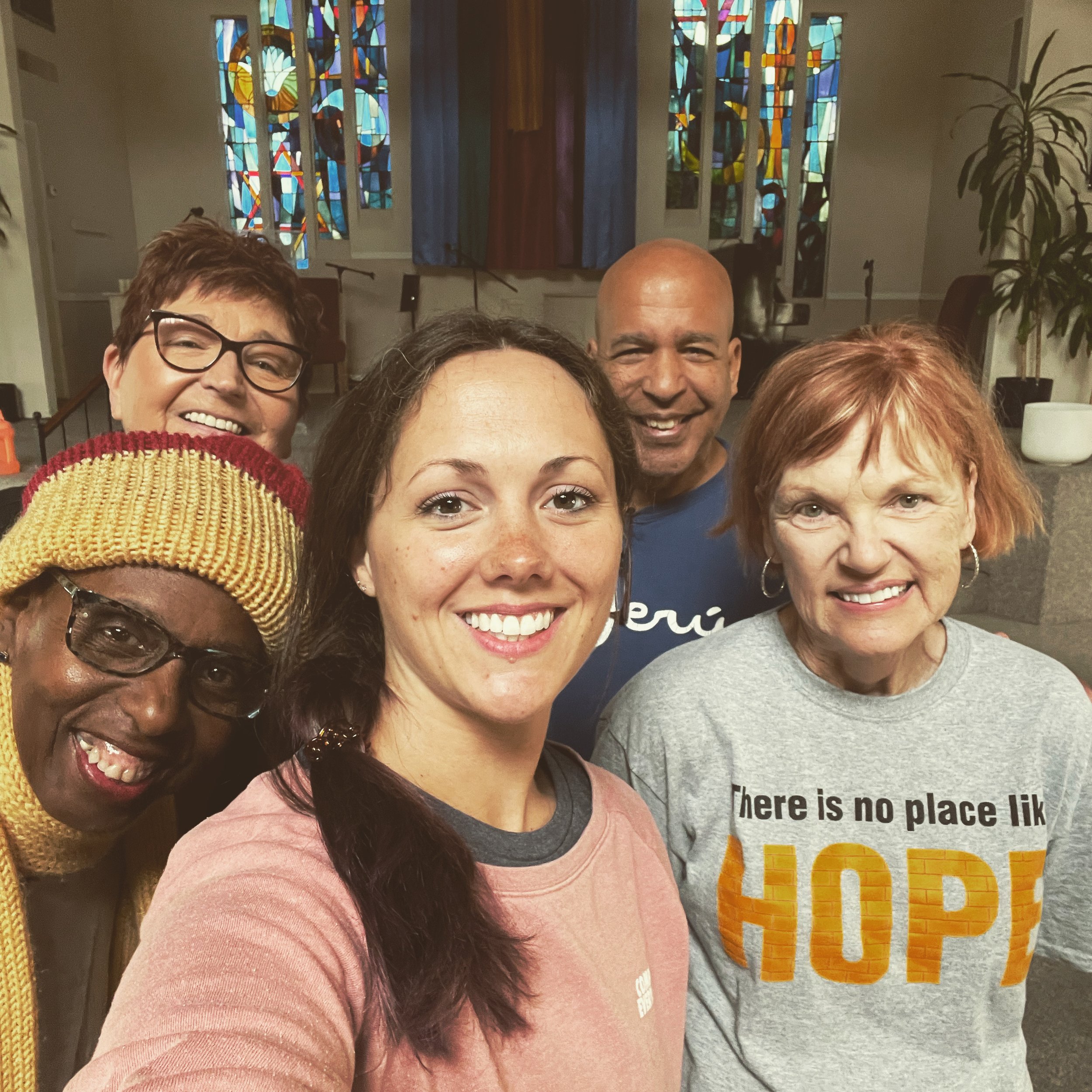 Group of four people smiling in a church with stained glass windows.