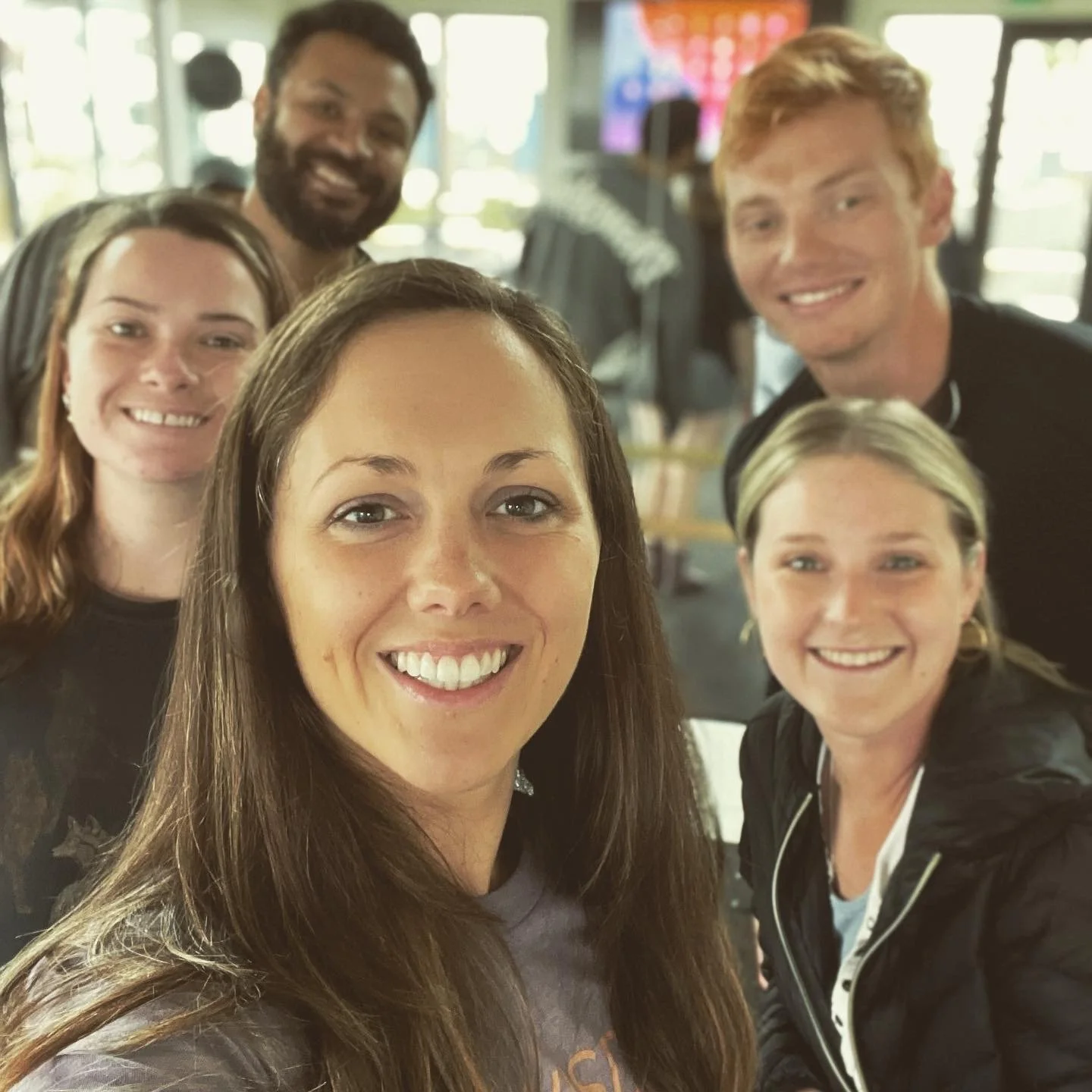 Group of five people indoors, smiling for a selfie.