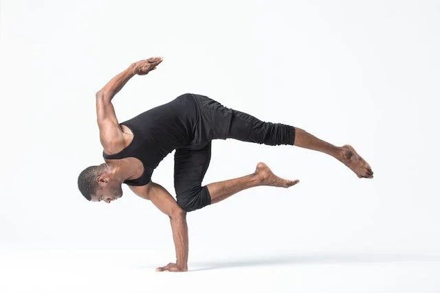 Man performing a complex yoga pose on white background