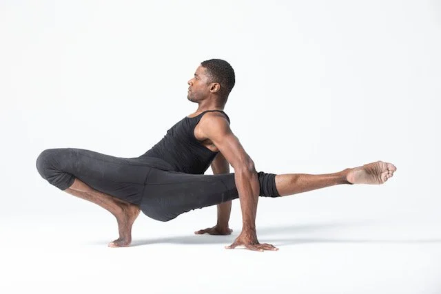 A man performing a yoga pose against a plain white background