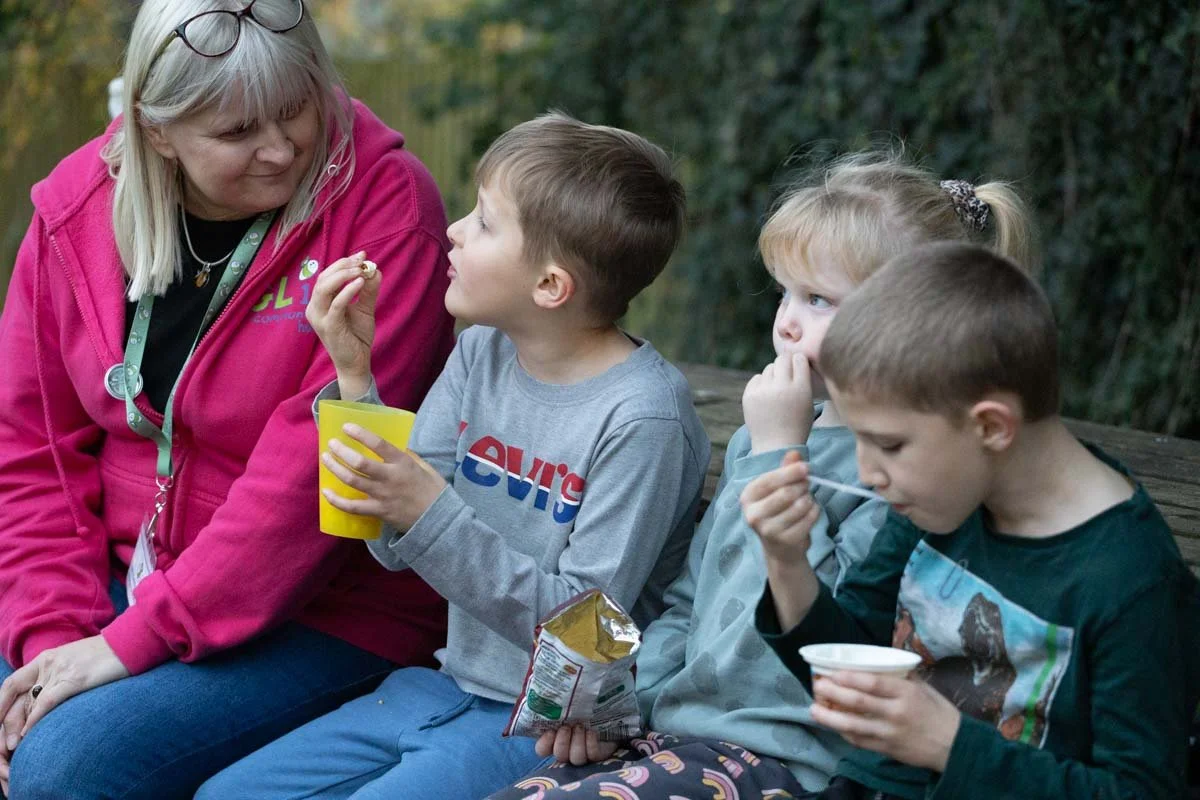 Kath from GL11 speaking to three children, who are eating snacks