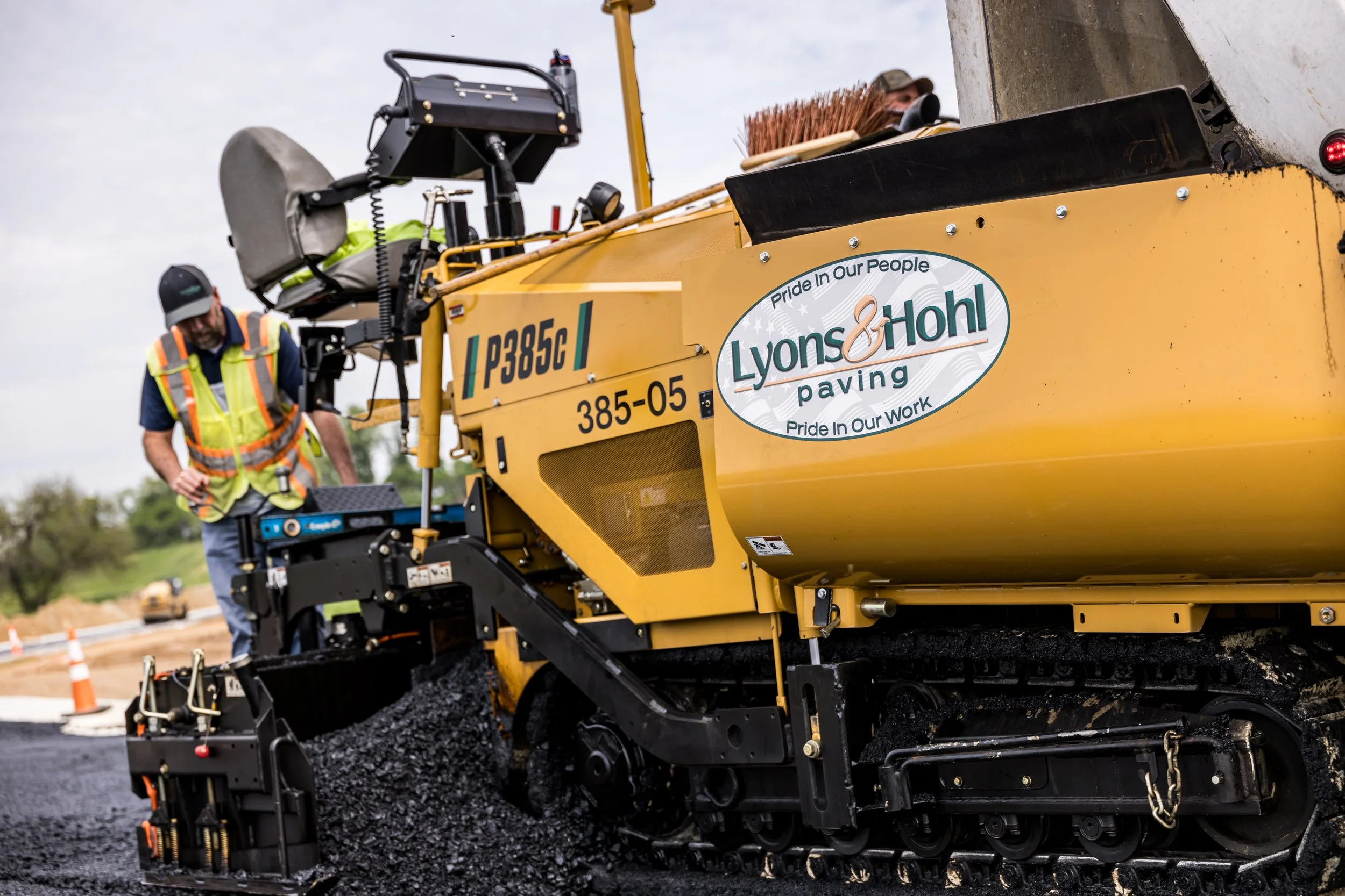 Paving crew running an asphalt paver laying down asphalt for new road