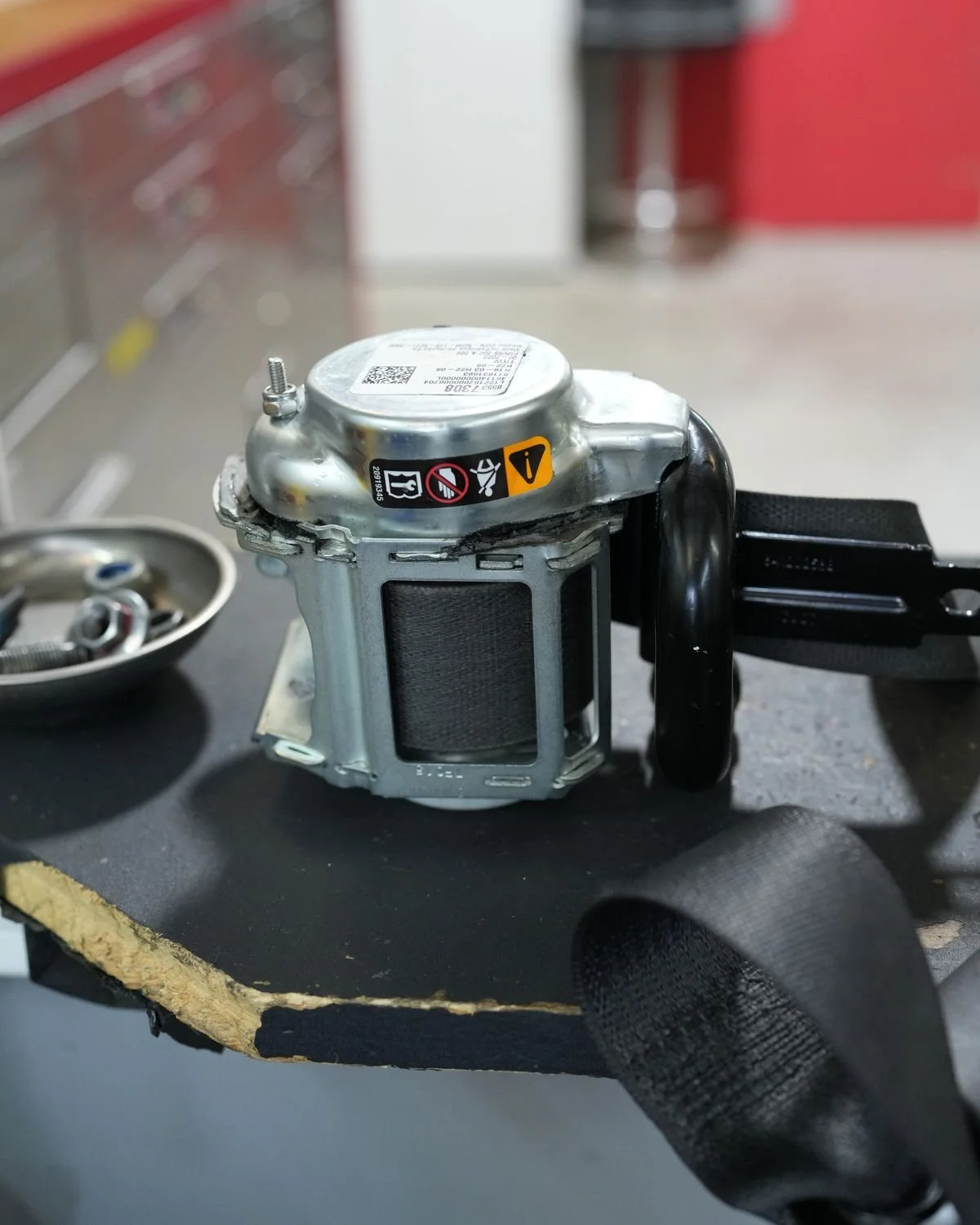 Seat belt retractor and pretensioner with black webbing on the repair bench