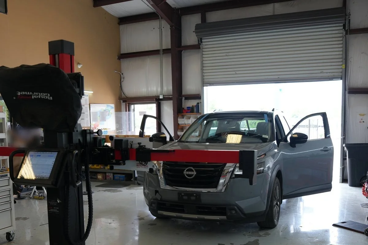 SUV in the shop facing an ADAS calibration frame, with the frame crossbar set at its front bumper