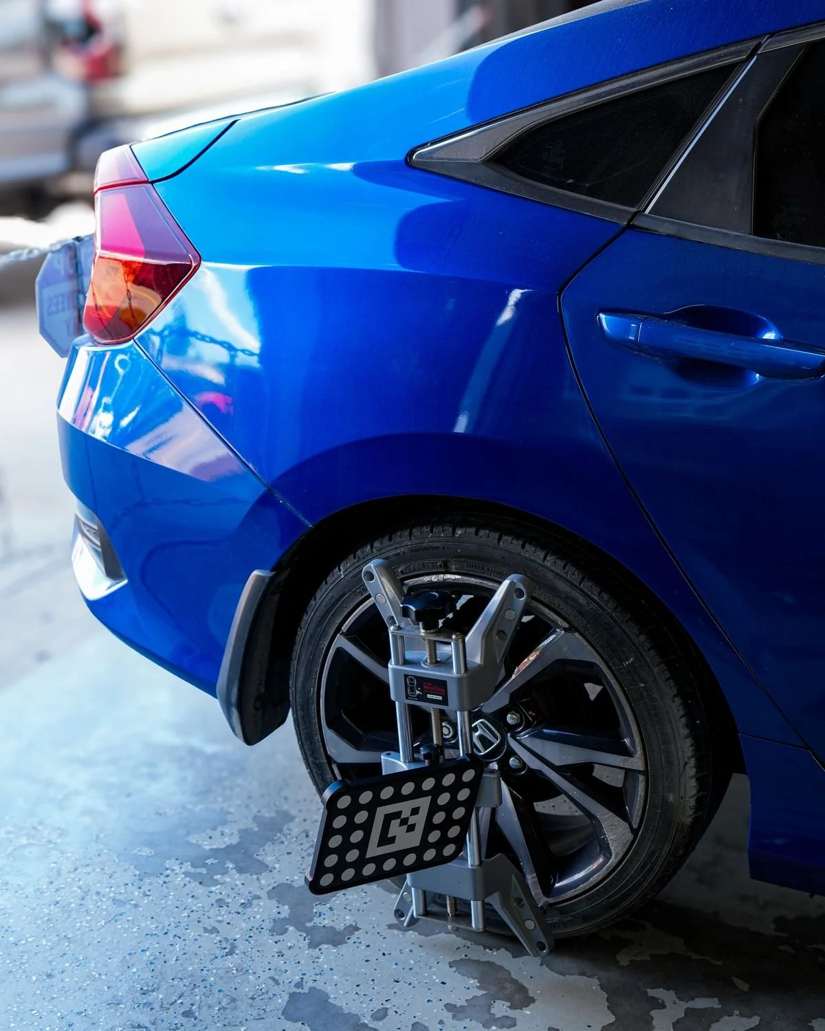 Wheel clamp with a target board mounted on a blue Honda's rear wheel during calibration setup
