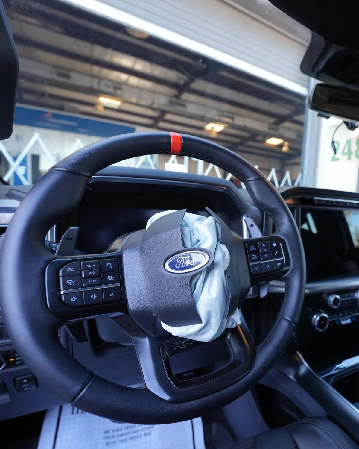 Deployed driver airbag hanging from the steering wheel of a vehicle in the shop