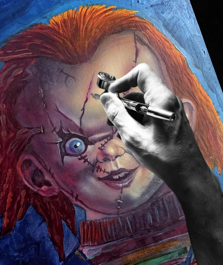 A person is painting a portrait of Chucky, the doll from horror movies, on a canvas. The painting depicts Chucky's face with a stitched scar and bright red hair.