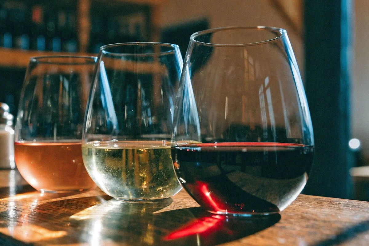 Three glasses of wine in stemless wine glasses.