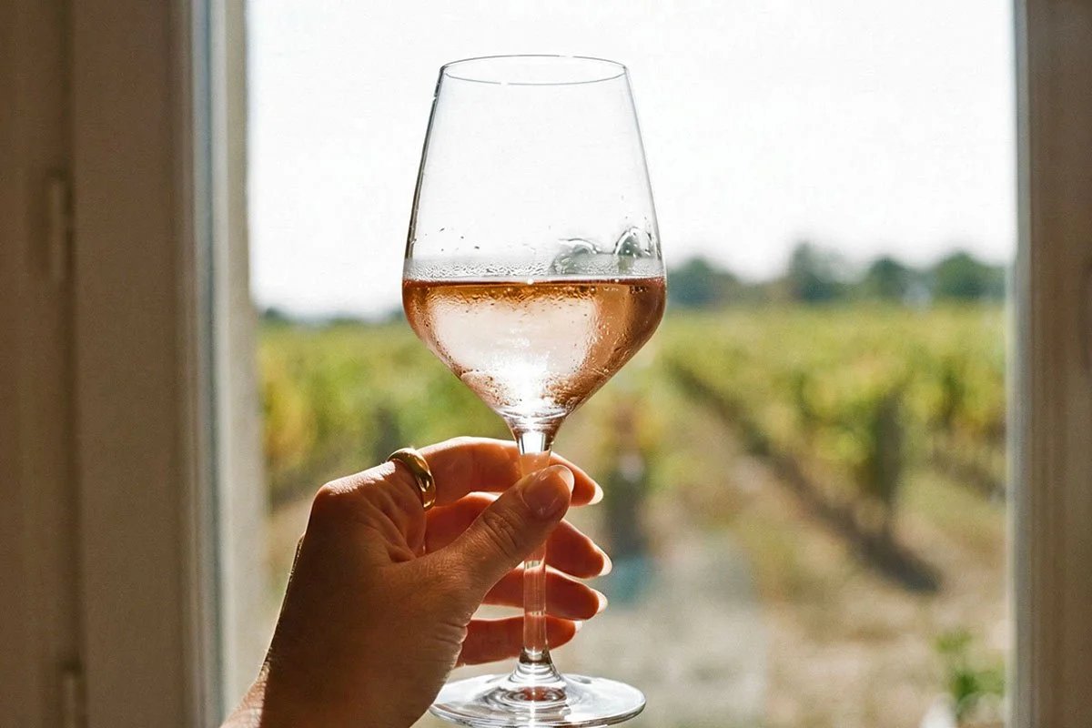 Hand holding a glass of rose wine up to the light.