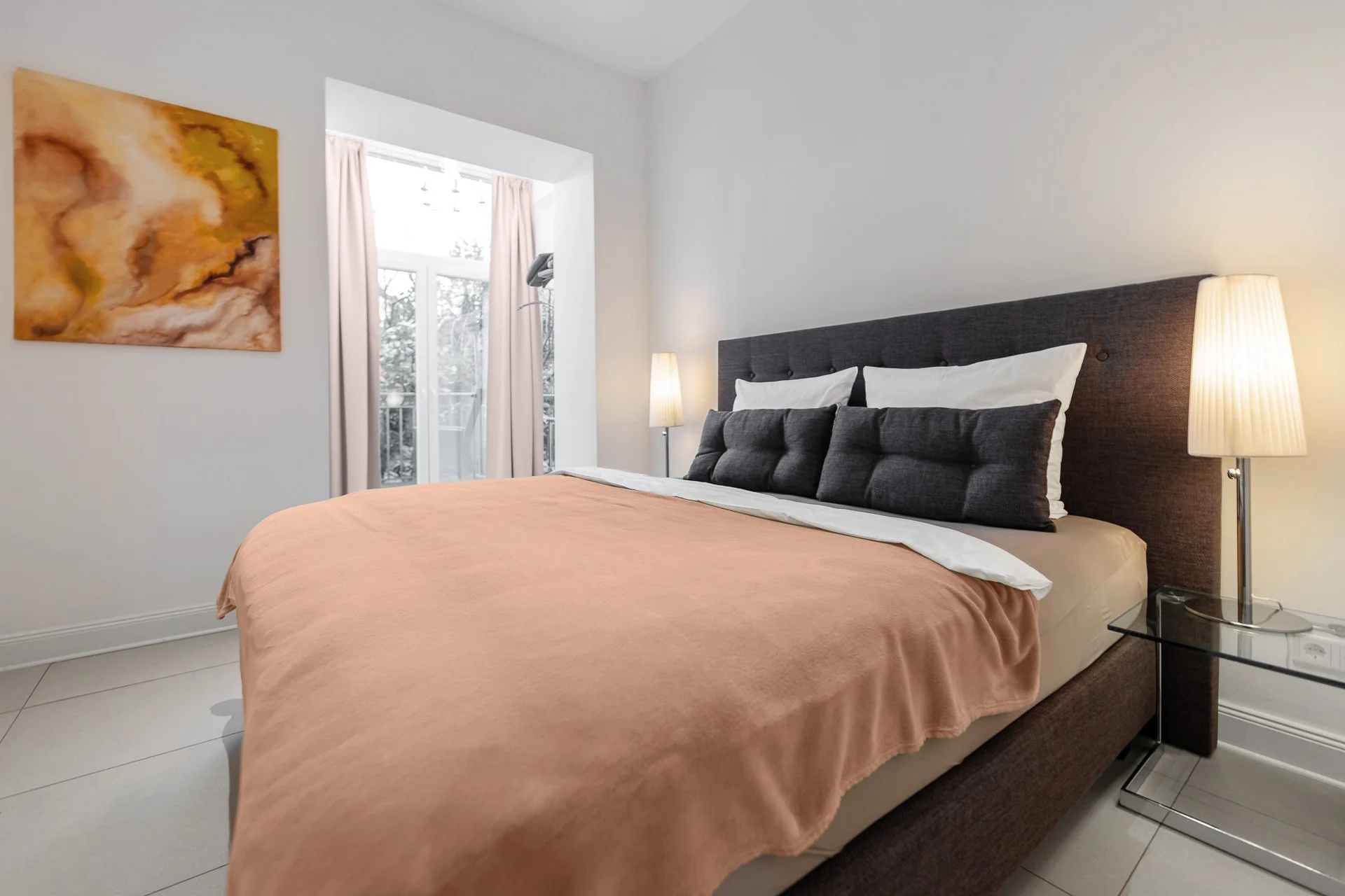 Modernes Schlafzimmer mit Doppelbett, seitlichem Nachttisch und Stehlampe, großem Fenster mit Vorhängen und abstraktem Gemälde an der Wand.