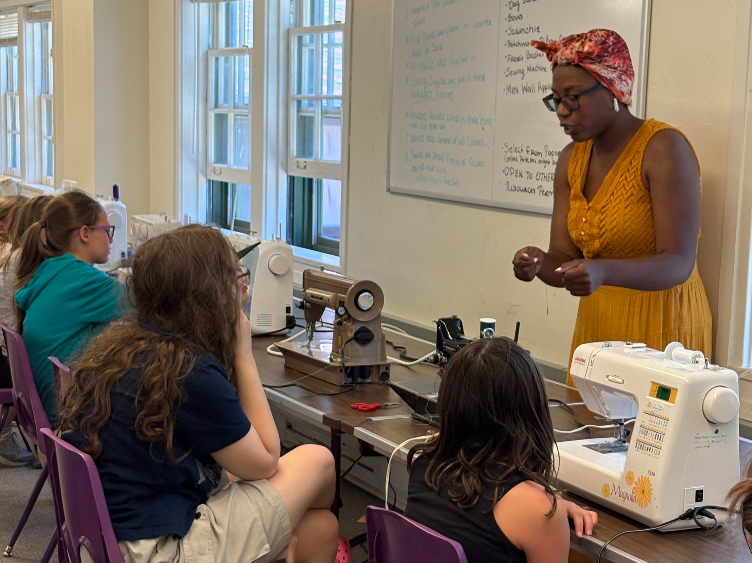 woman teaching students in front of sewing machines