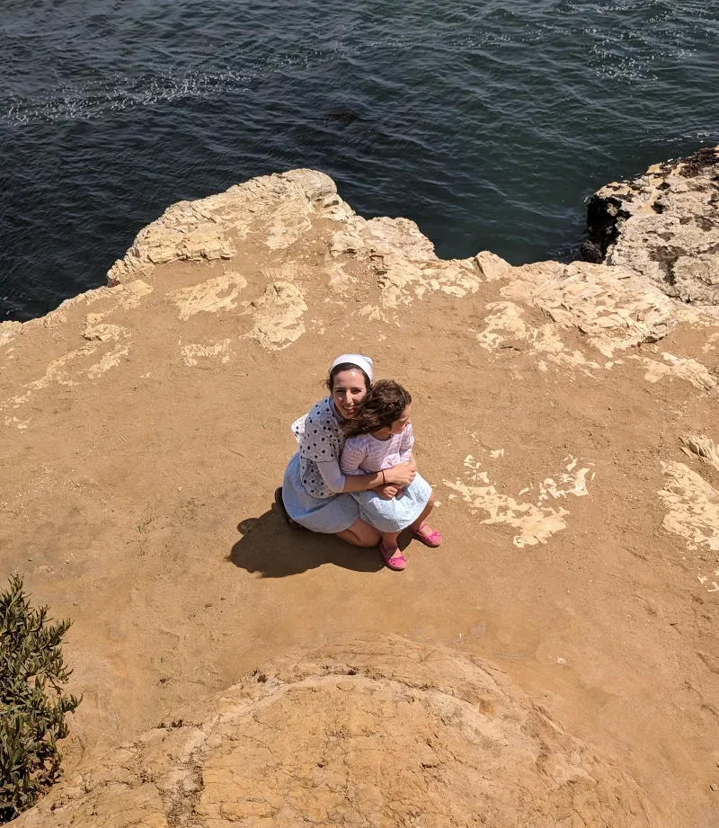 Mother holding her young child beside the sea.
