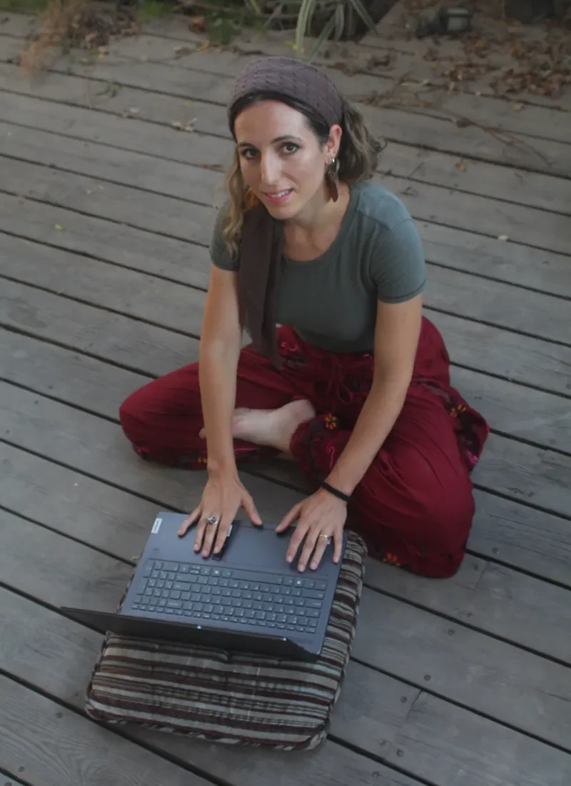 Ruthie Ayzenberg seated outdoors with a laptop.