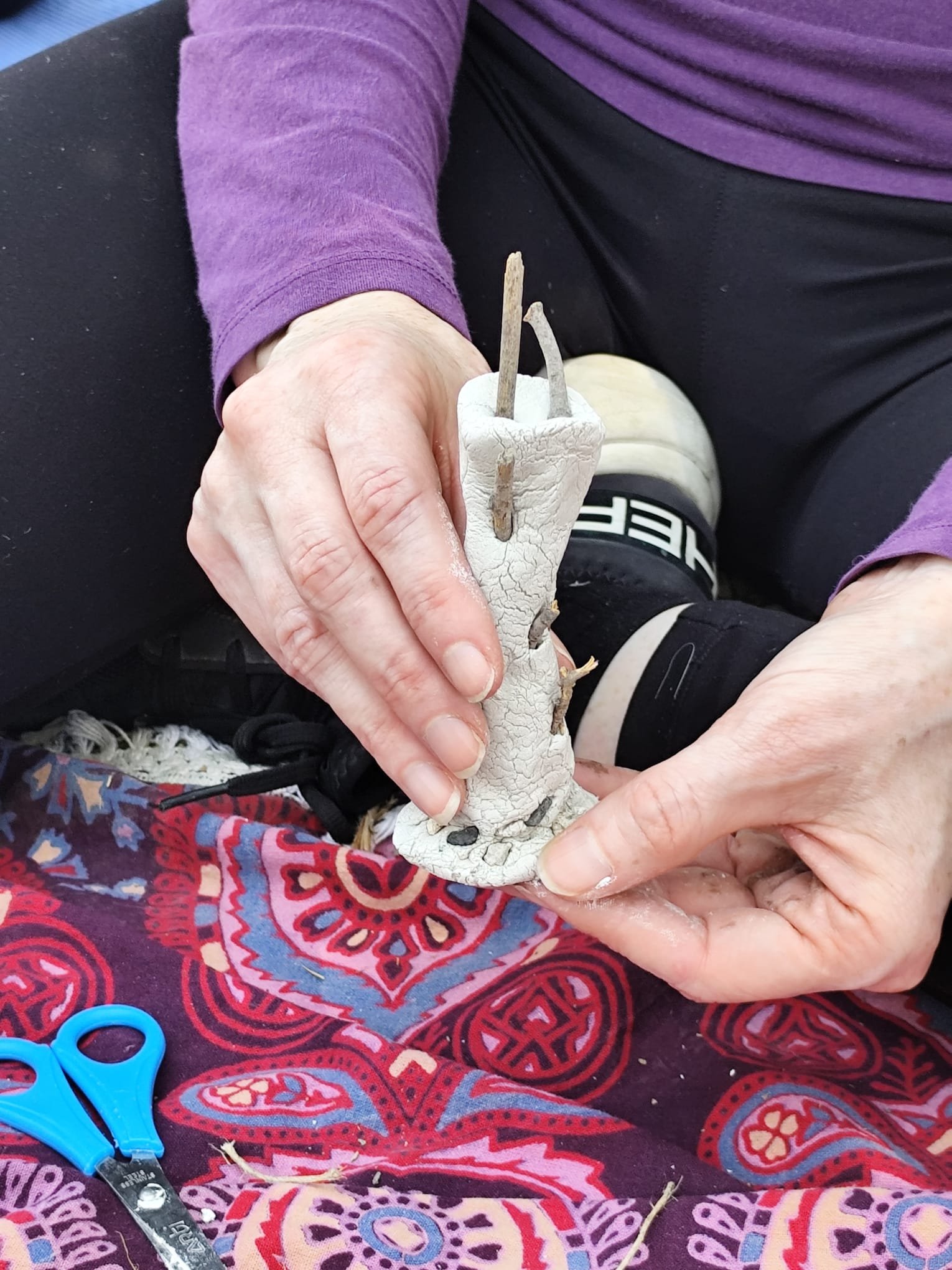 Hands creating a small clay figure during a creative workshop.