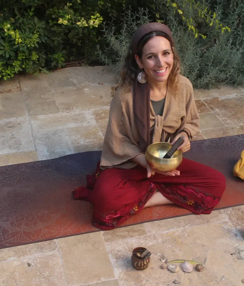 Ruthie Ayzenberg, psychoterapist and yoga teacher, holding a singing bowl during an outdoor mindfulness practice.
