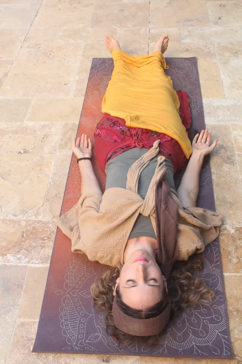 Ruthie Ayzenberg resting on a yoga mat during a Yoga Nidra practice.