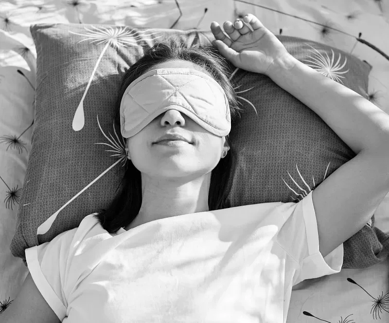 Person resting with an eye mask during a ketamine assisted psychotherapy dosing session.