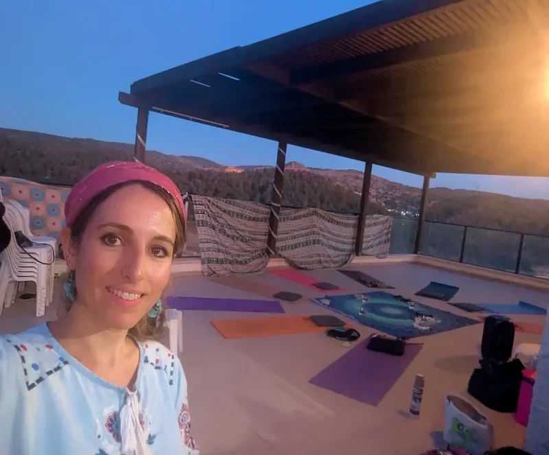 Ruthie Ayzenberg at an outdoor yoga gathering at sunset.