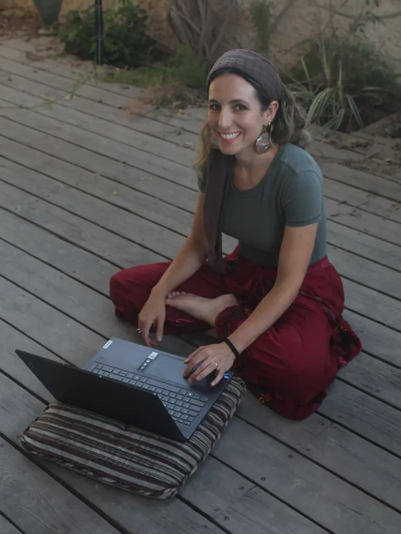 Ruthie Ayzenberg working outdoors on a laptop.