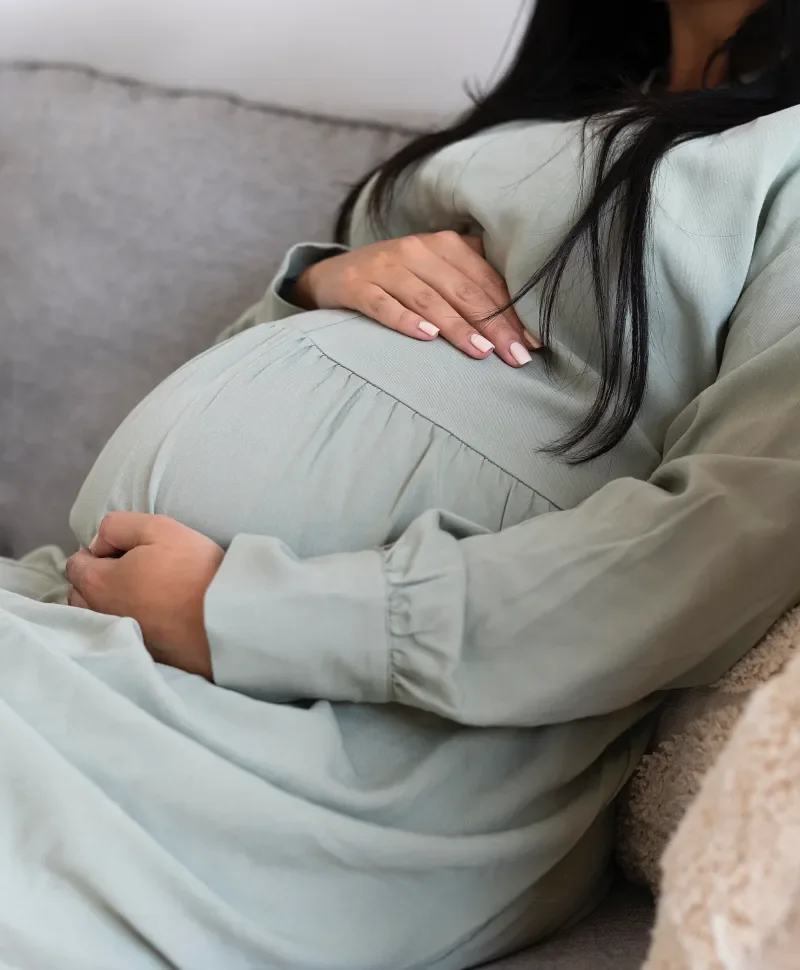 Pregnant person sitting comfortably with their hands on their belly.