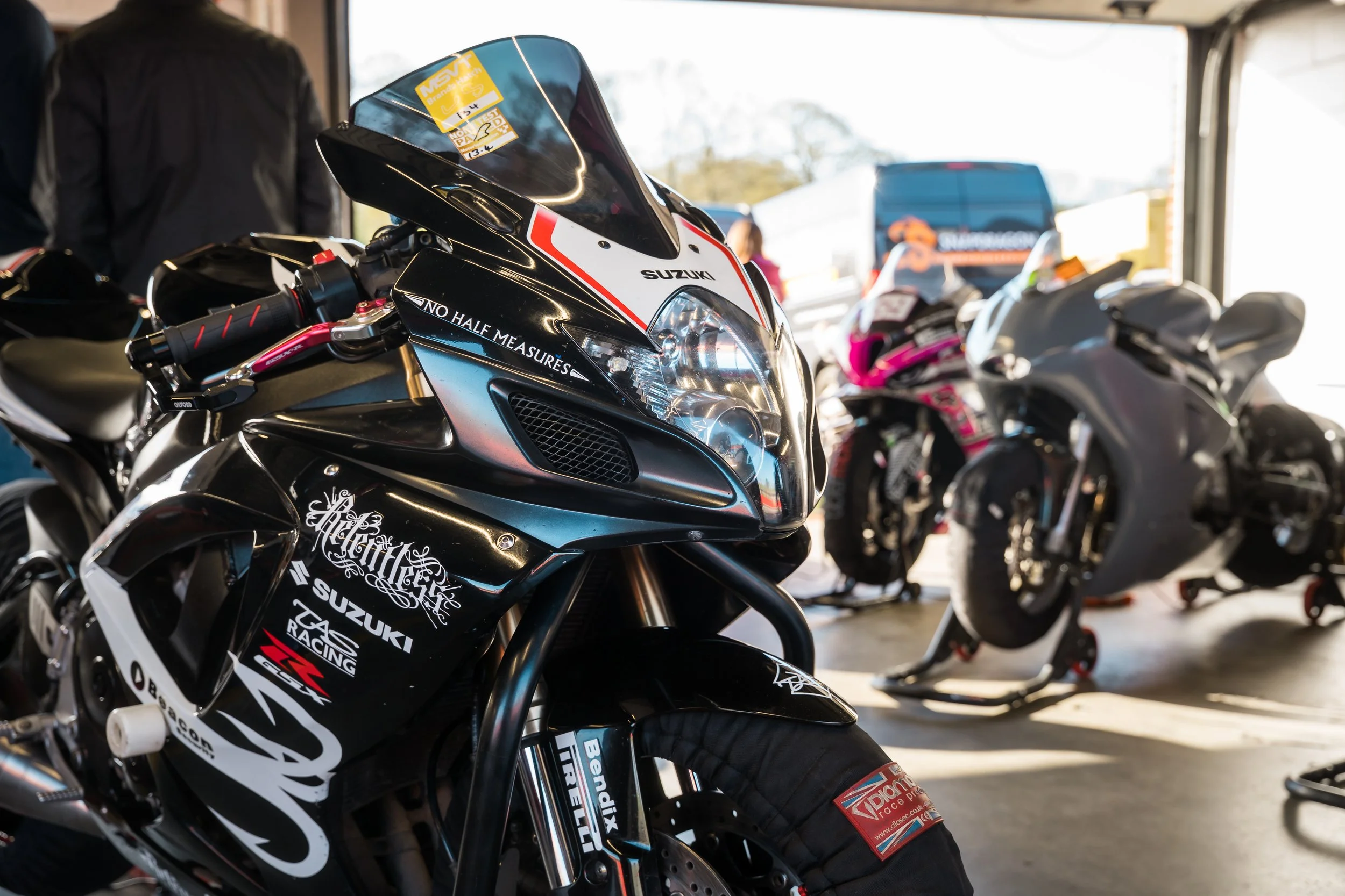 Close-up of a black Suzuki race motorcycle in a garage with other motorcycles in the background.