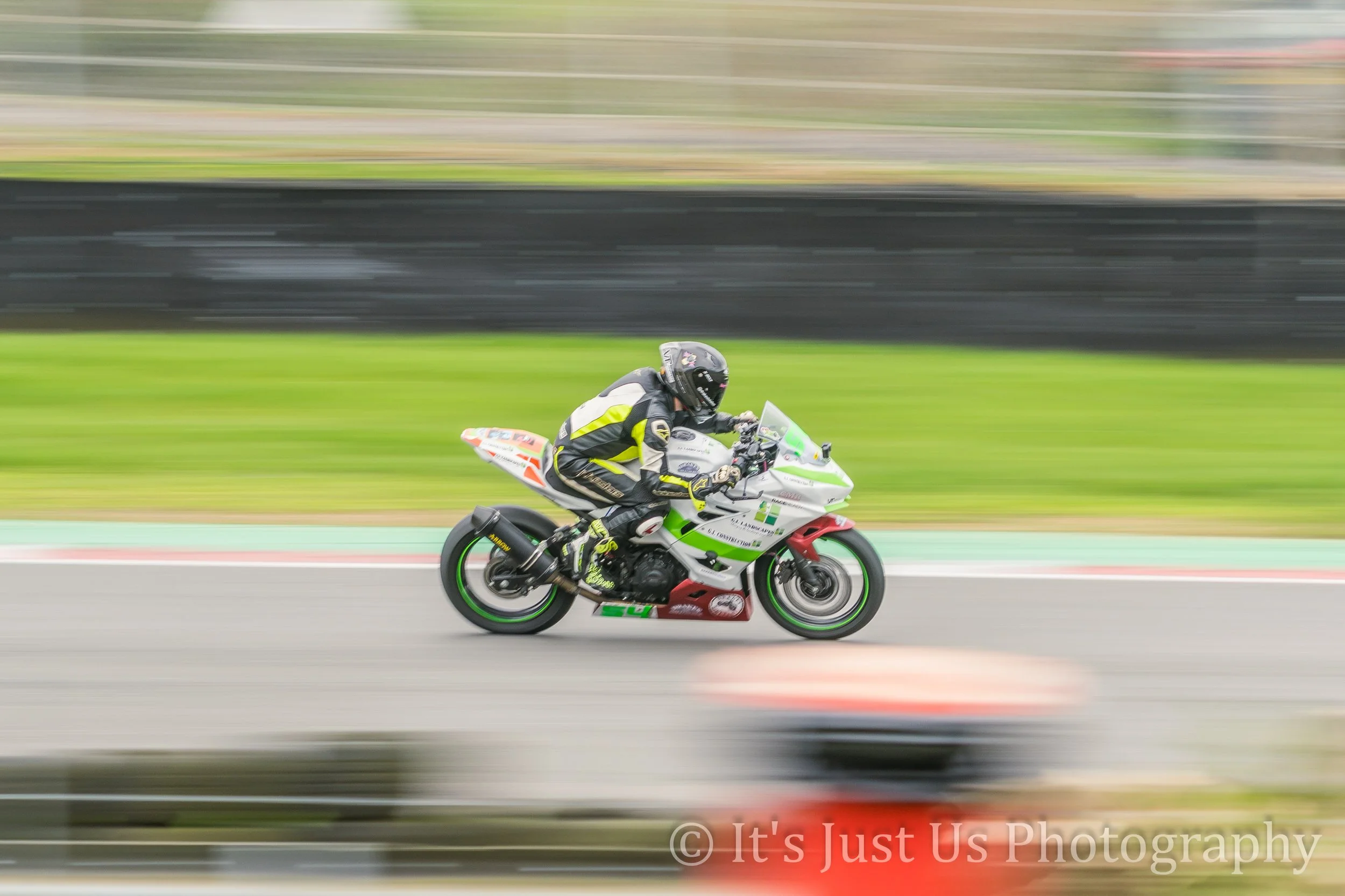Motorcycle racer in racing gear riding on track with motion blur background.
