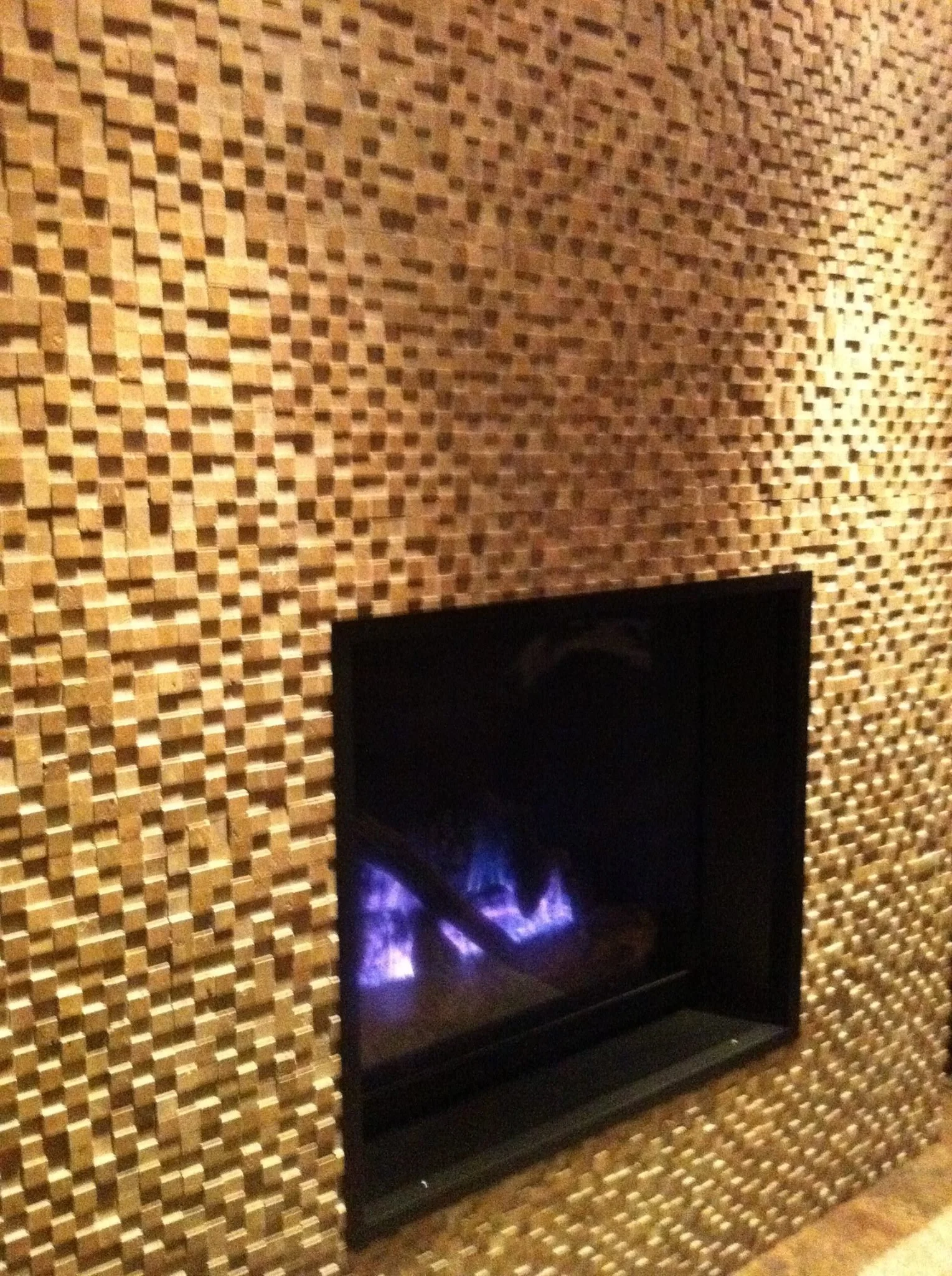 Close-up of a modern fireplace embedded in a wall with a textured wooden or tile surface.
