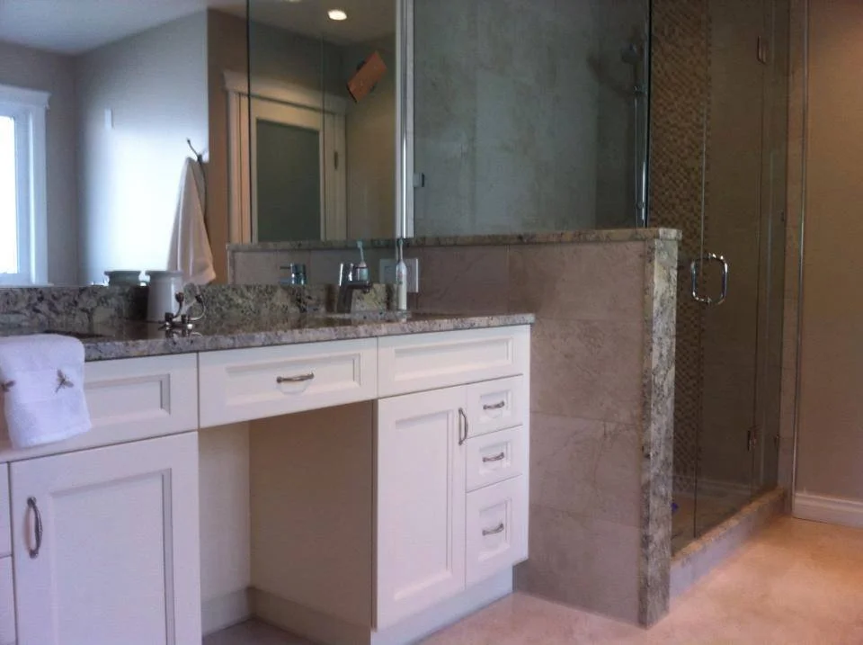 Bathroom with white vanity, granite countertop, and a glass shower enclosure.