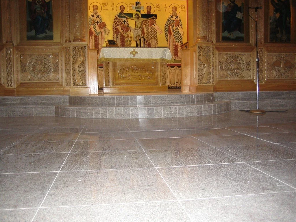Interior of an Orthodox Christian church with religious icons and a shrine at the altar, featuring a detailed gold and wood iconostasis.