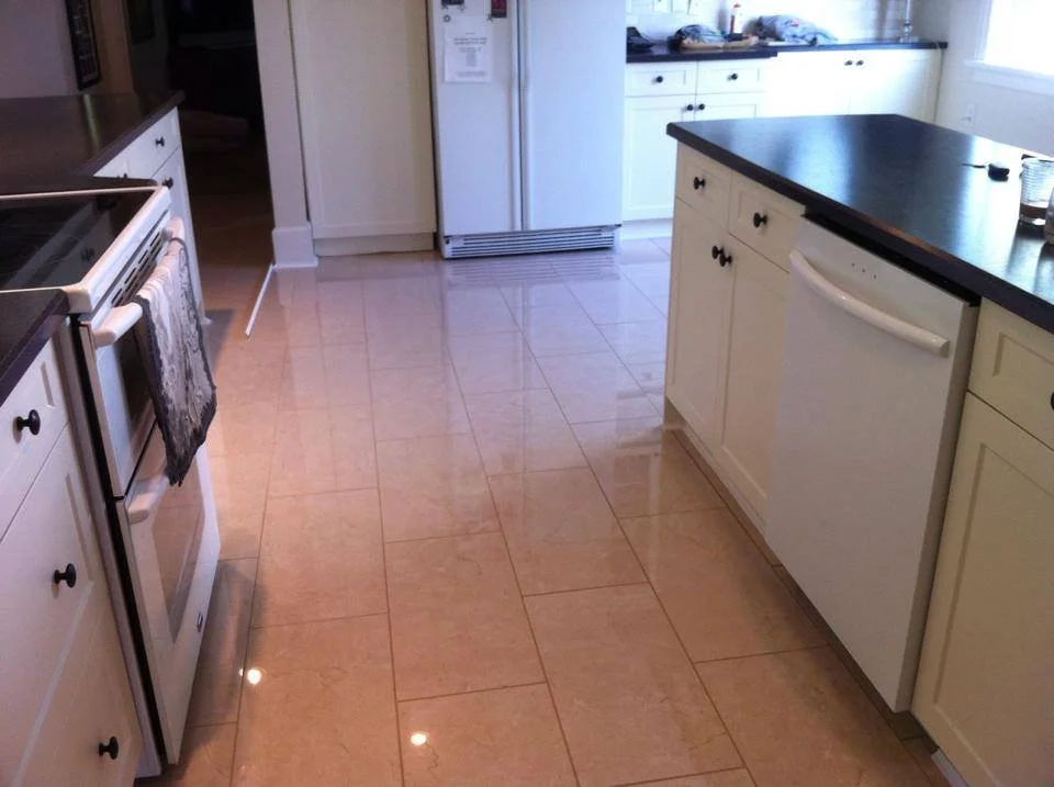 Kitchen with white cabinets, black countertops, and beige tile floor. Includes a stove, refrigerator, and dishwasher.