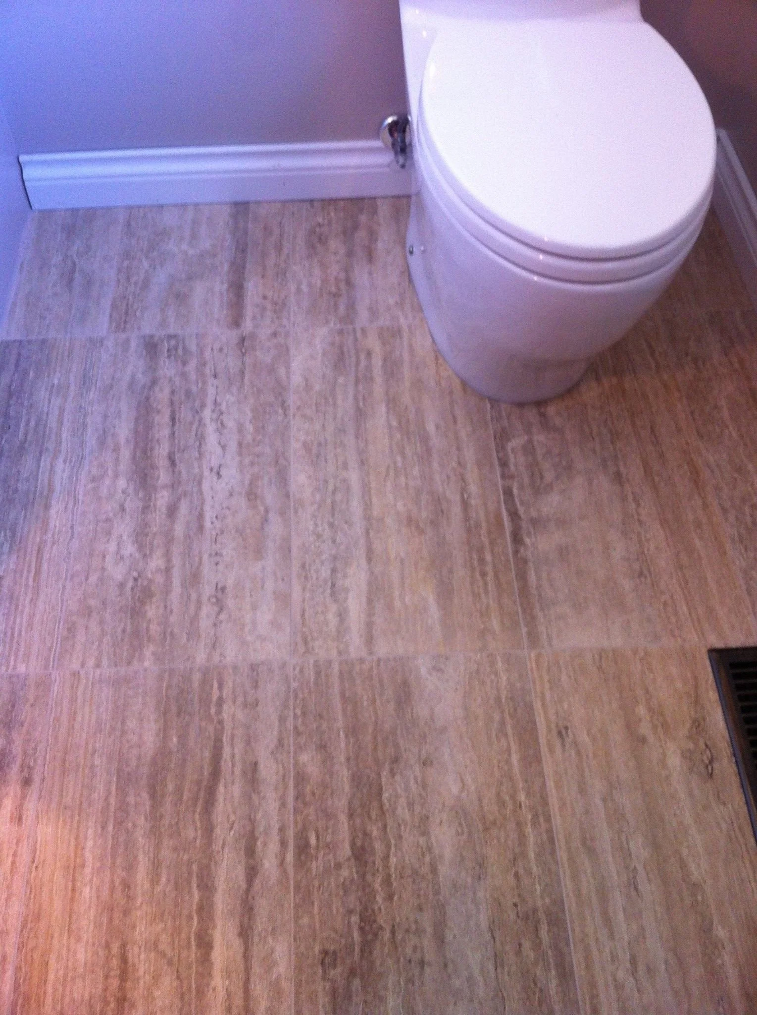 A bathroom with beige tile flooring and a white toilet near the wall